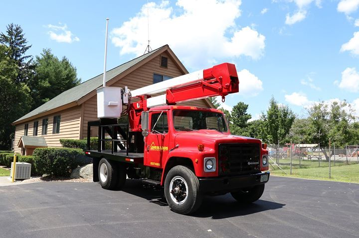 A red truck with a crane on the back is parked in front of a house.