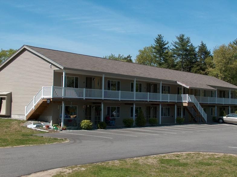 A large apartment building with a car parked in front of it.