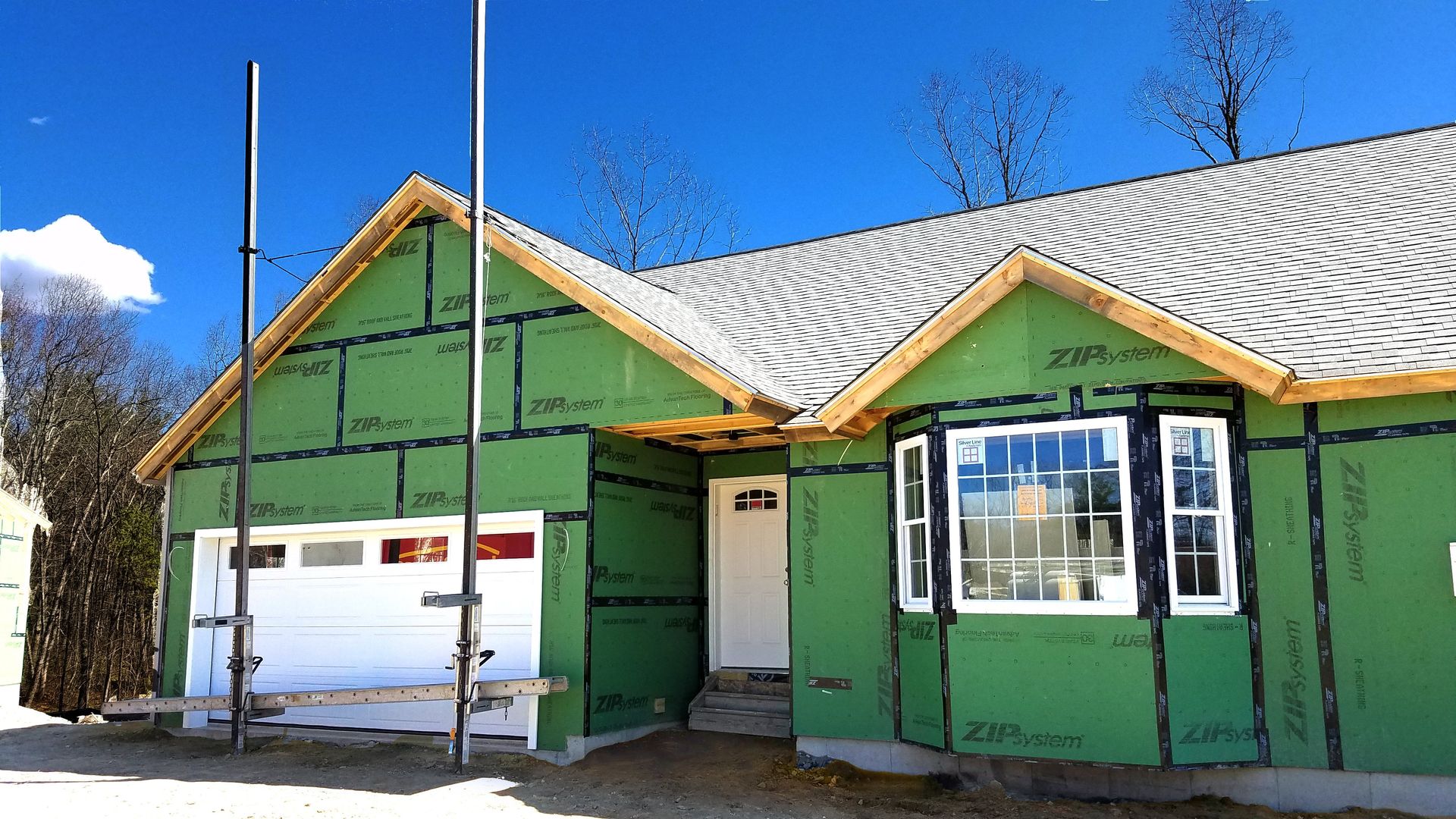 A house under construction with green siding and a white garage door