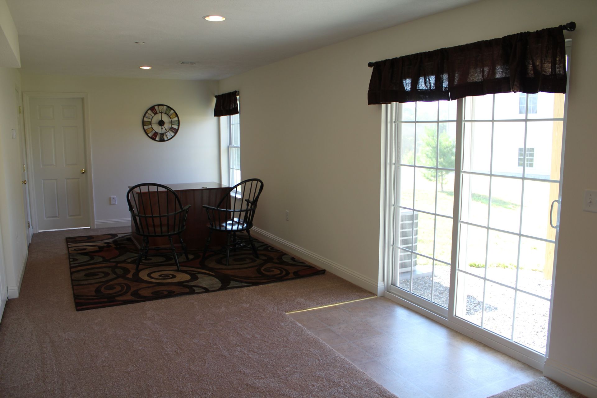 A living room with sliding glass doors and a clock on the wall
