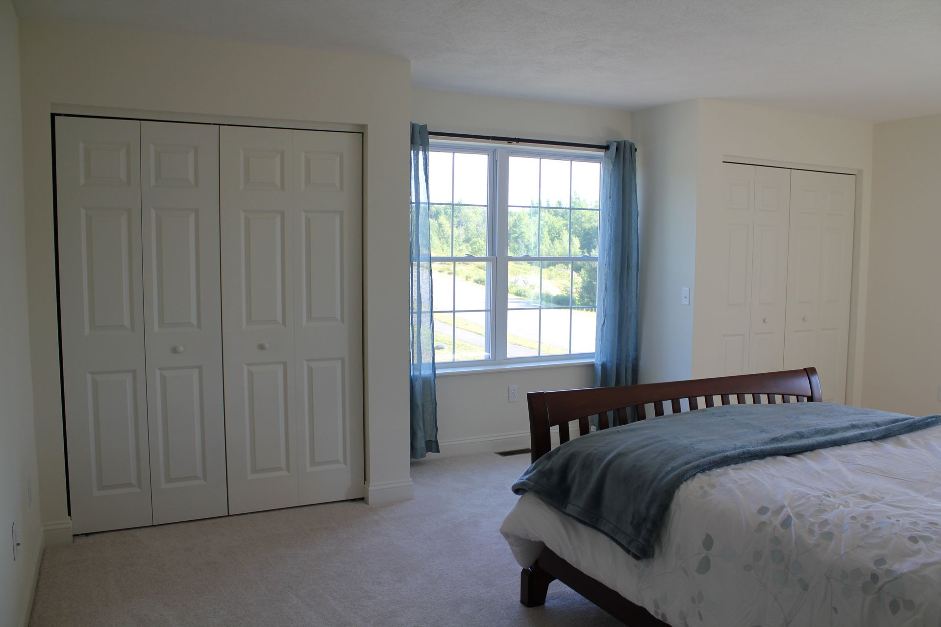 A bedroom with a bed , closets and a window