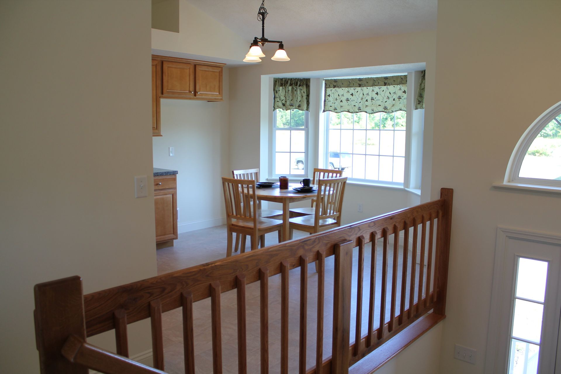 A wooden railing leads to a dining room with a table and chairs.