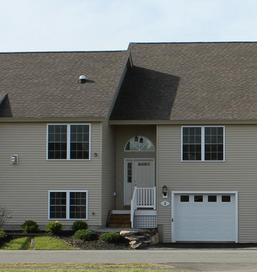A large beige house with a brown roof and a white garage door.