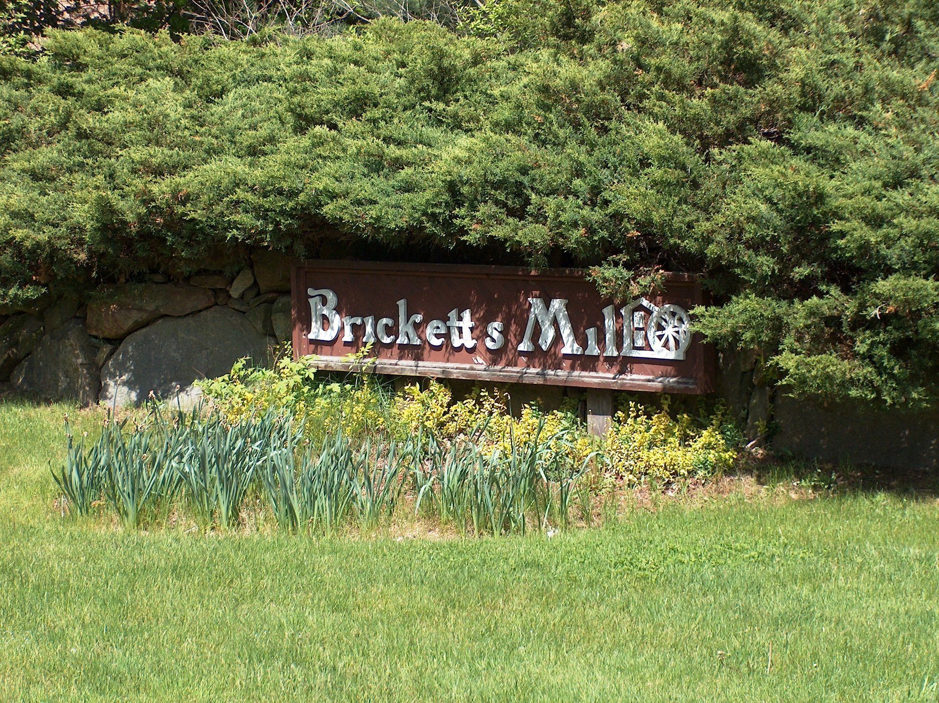 A sign for brickett 's miller is surrounded by trees and grass.