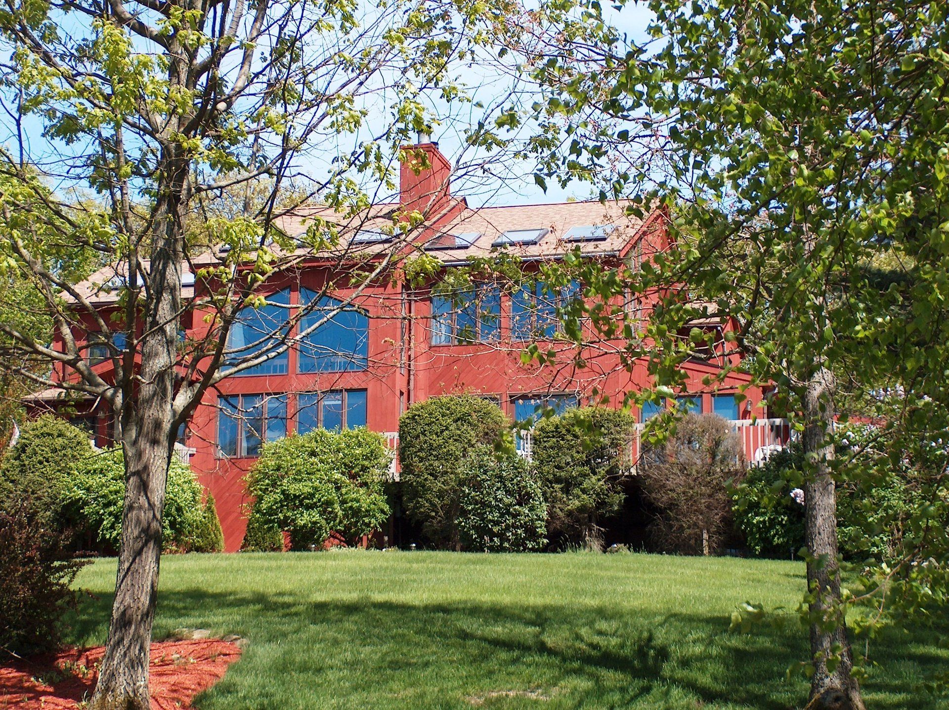 A large red building with blue windows is surrounded by trees and grass.