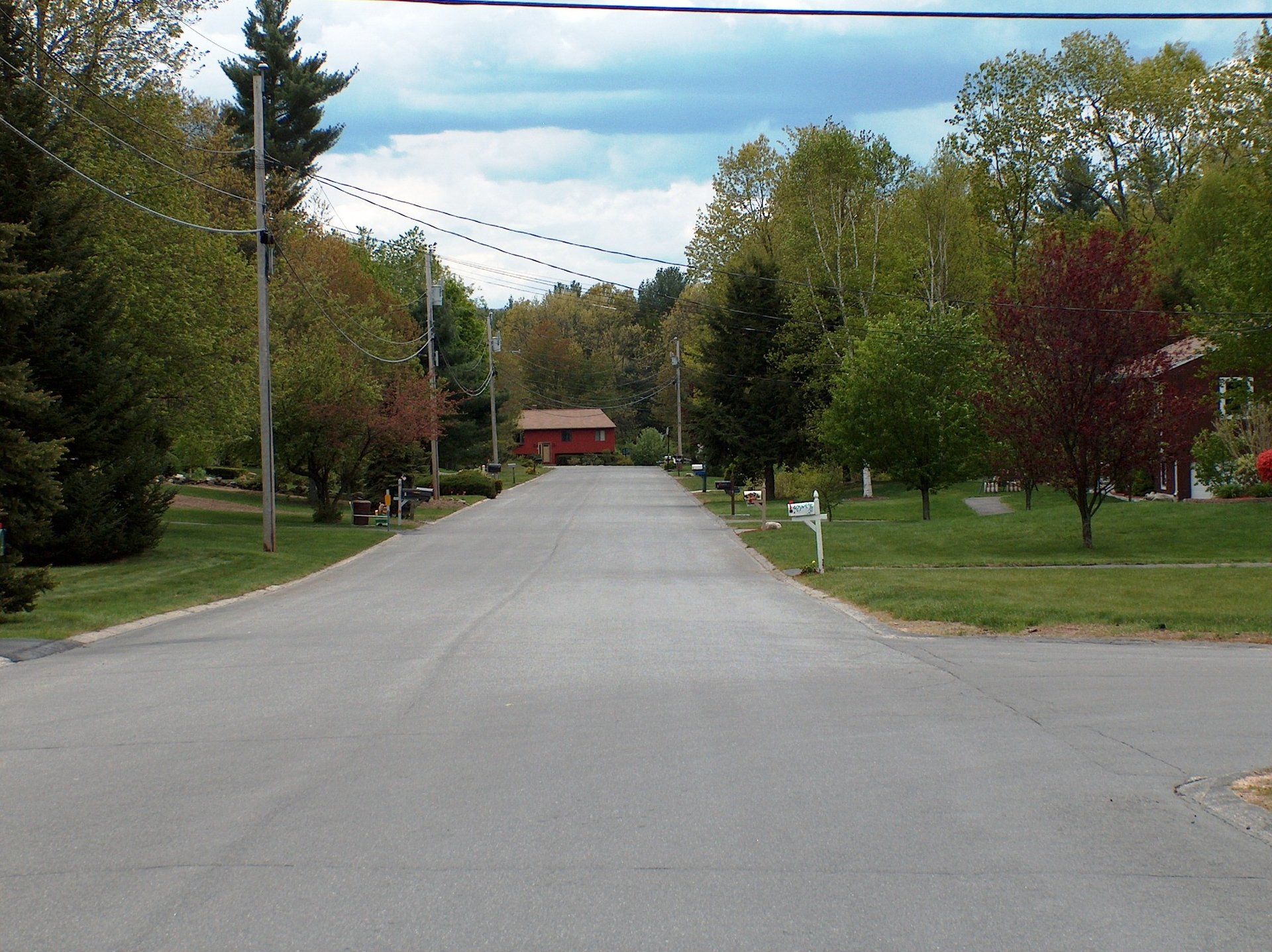 An empty street with a white mailbox in the middle
