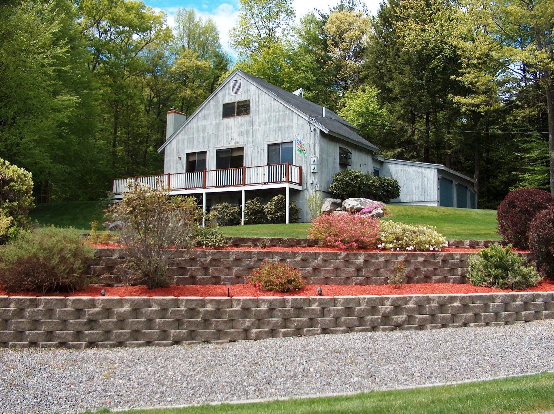 A white house sits on top of a hill surrounded by trees