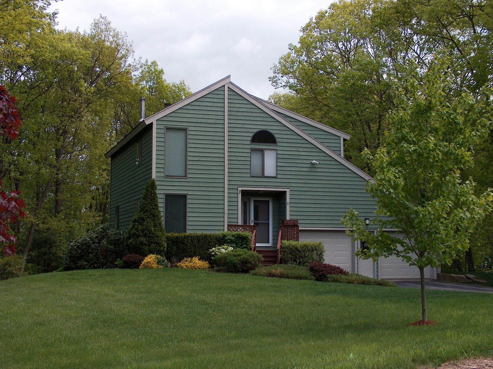 A green house is surrounded by trees and grass