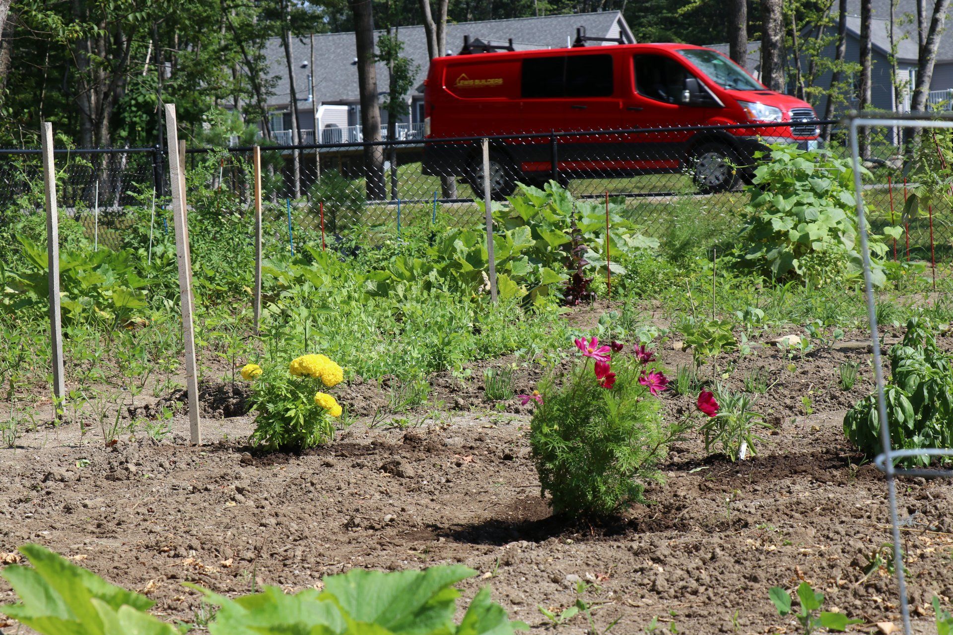 A red van is parked in the middle of a garden.
