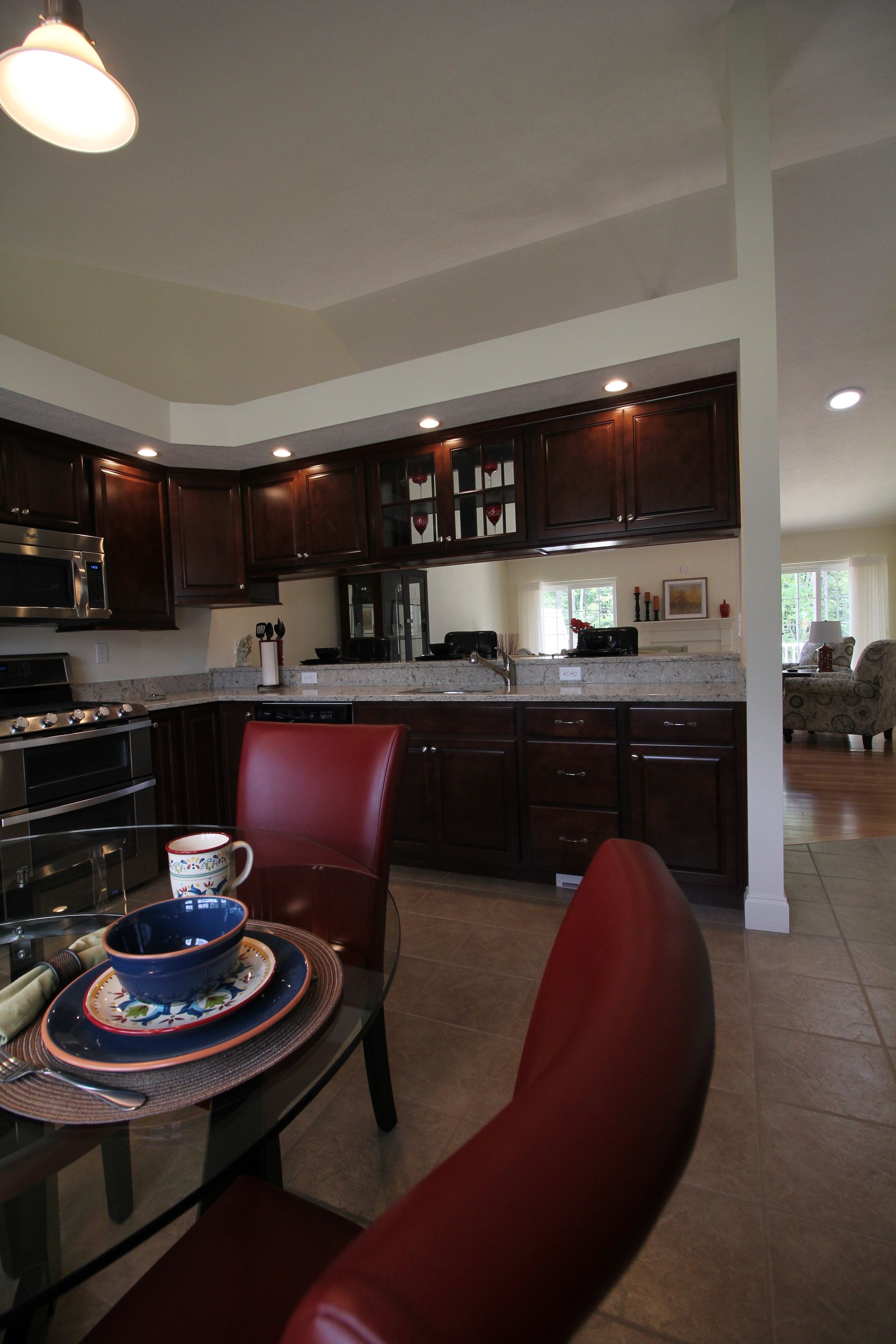 A kitchen with a glass table and red chairs