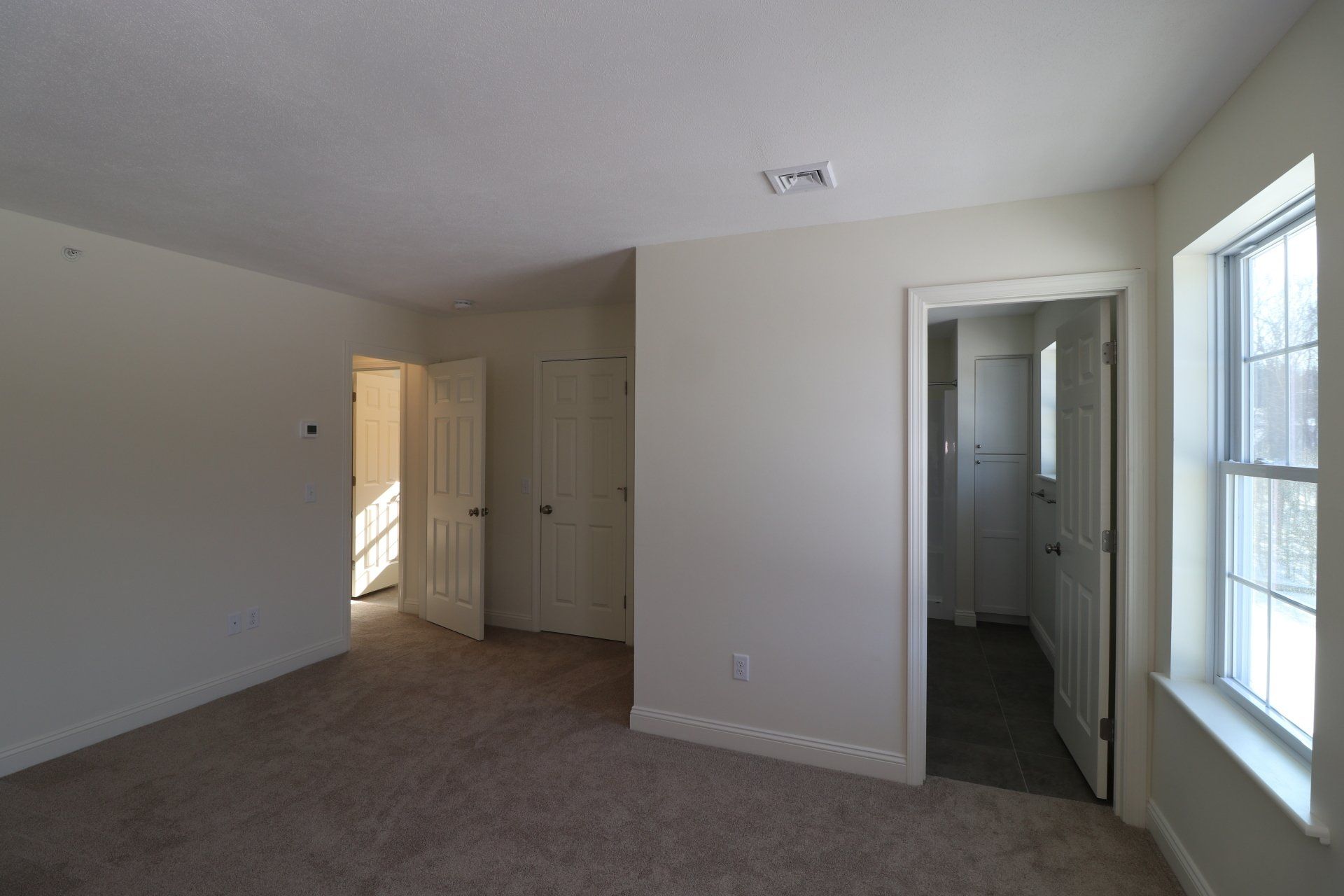 An empty bedroom with a carpeted floor and white walls