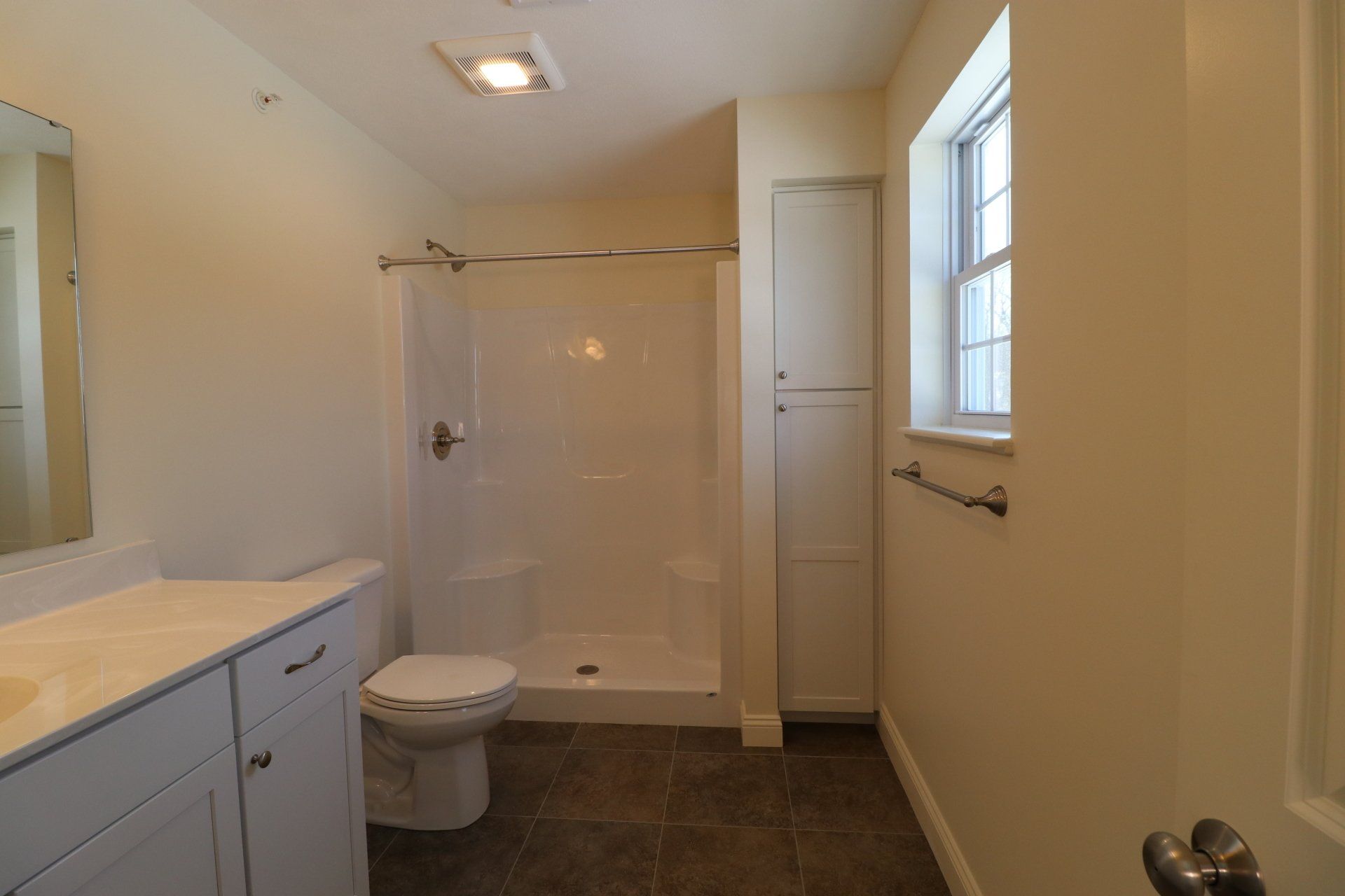 A bathroom with a toilet , sink and shower.