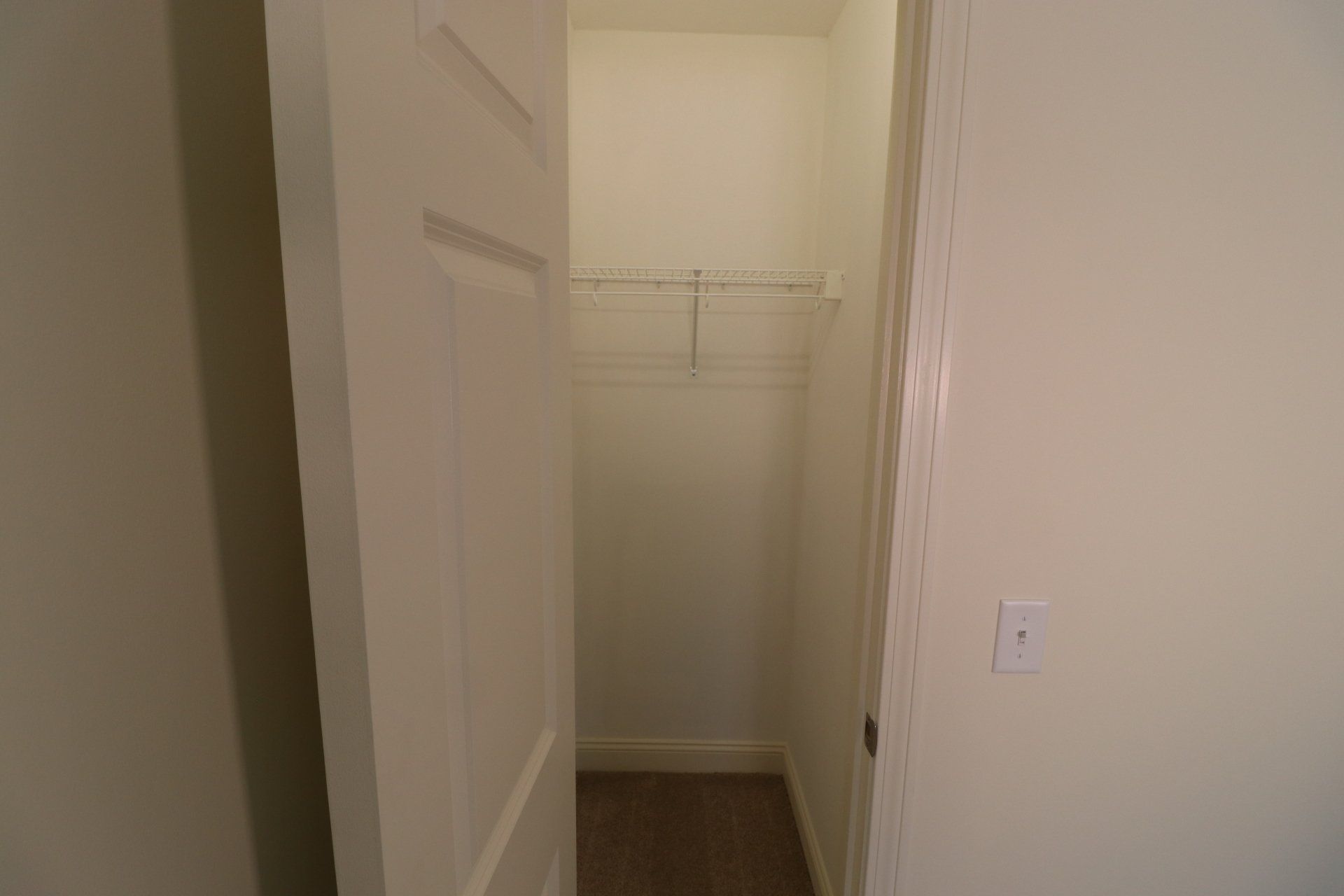 A closet with a door and a light switch on the wall.