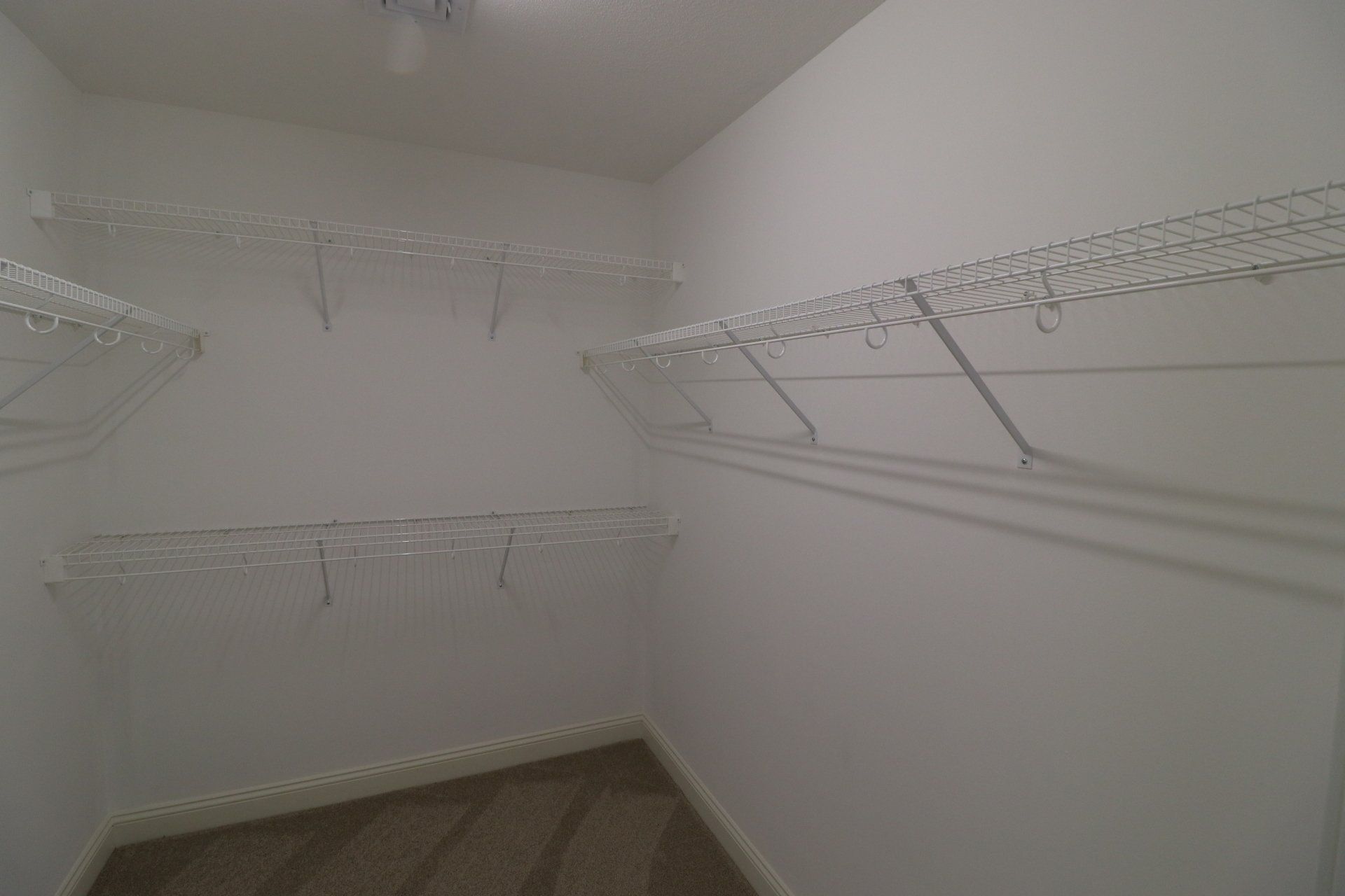 A walk in closet with lots of shelves and clothes racks.