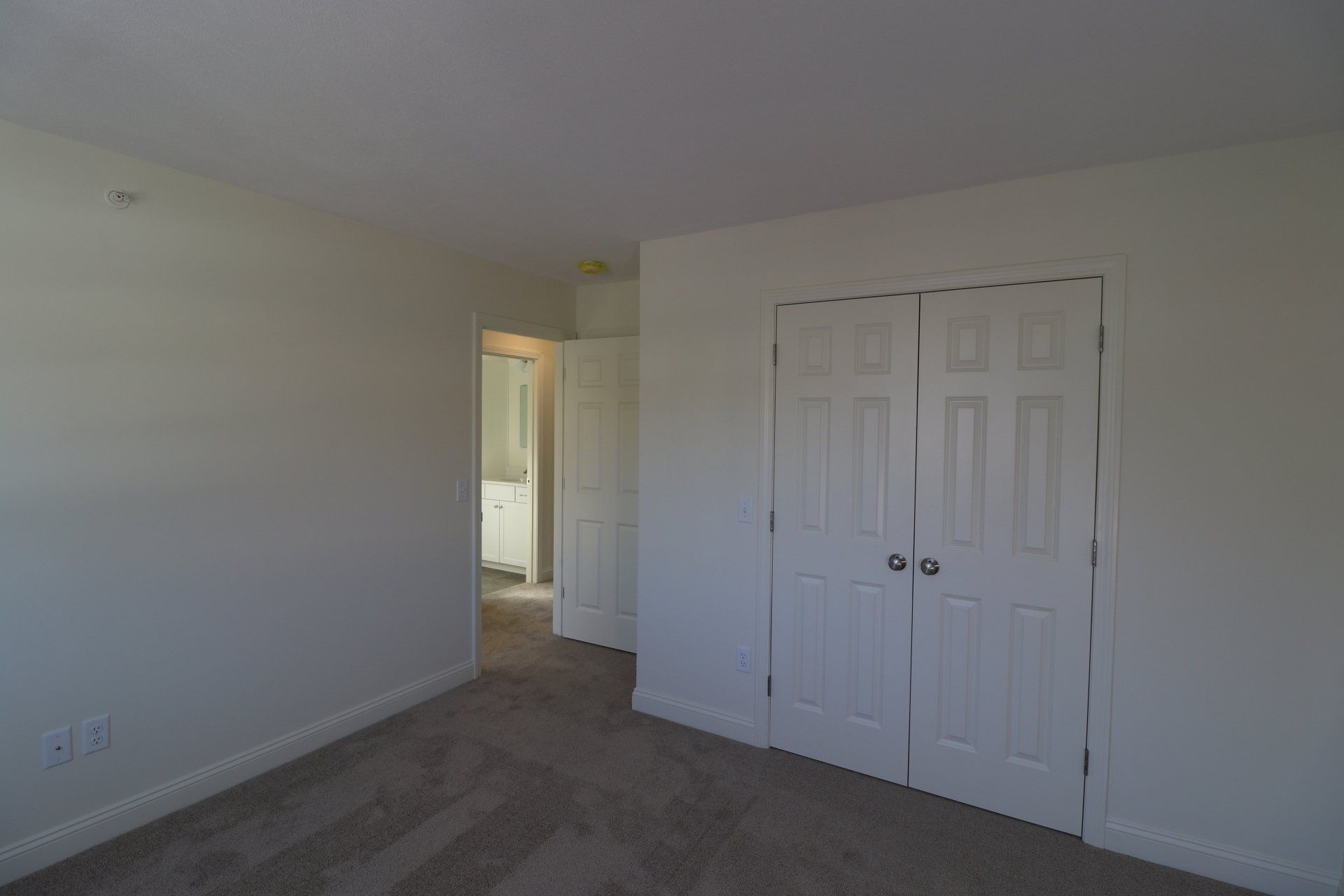 An empty bedroom with white walls and a closet.