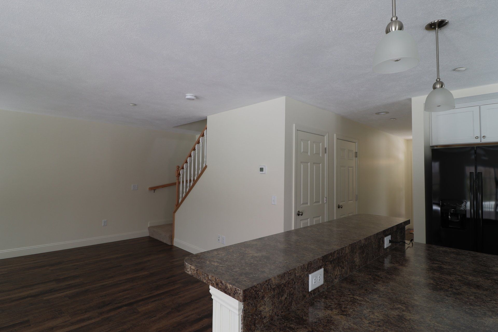 A kitchen with a granite counter top and a staircase in the background.