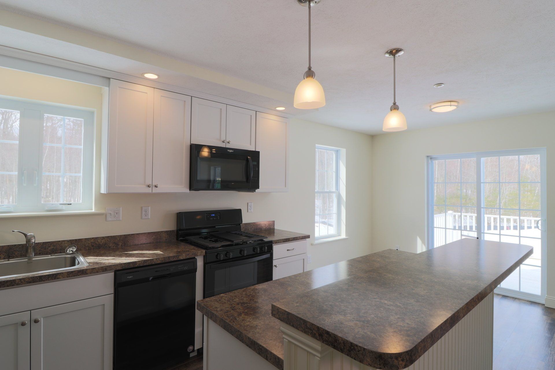 An empty kitchen with white cabinets and granite counter tops