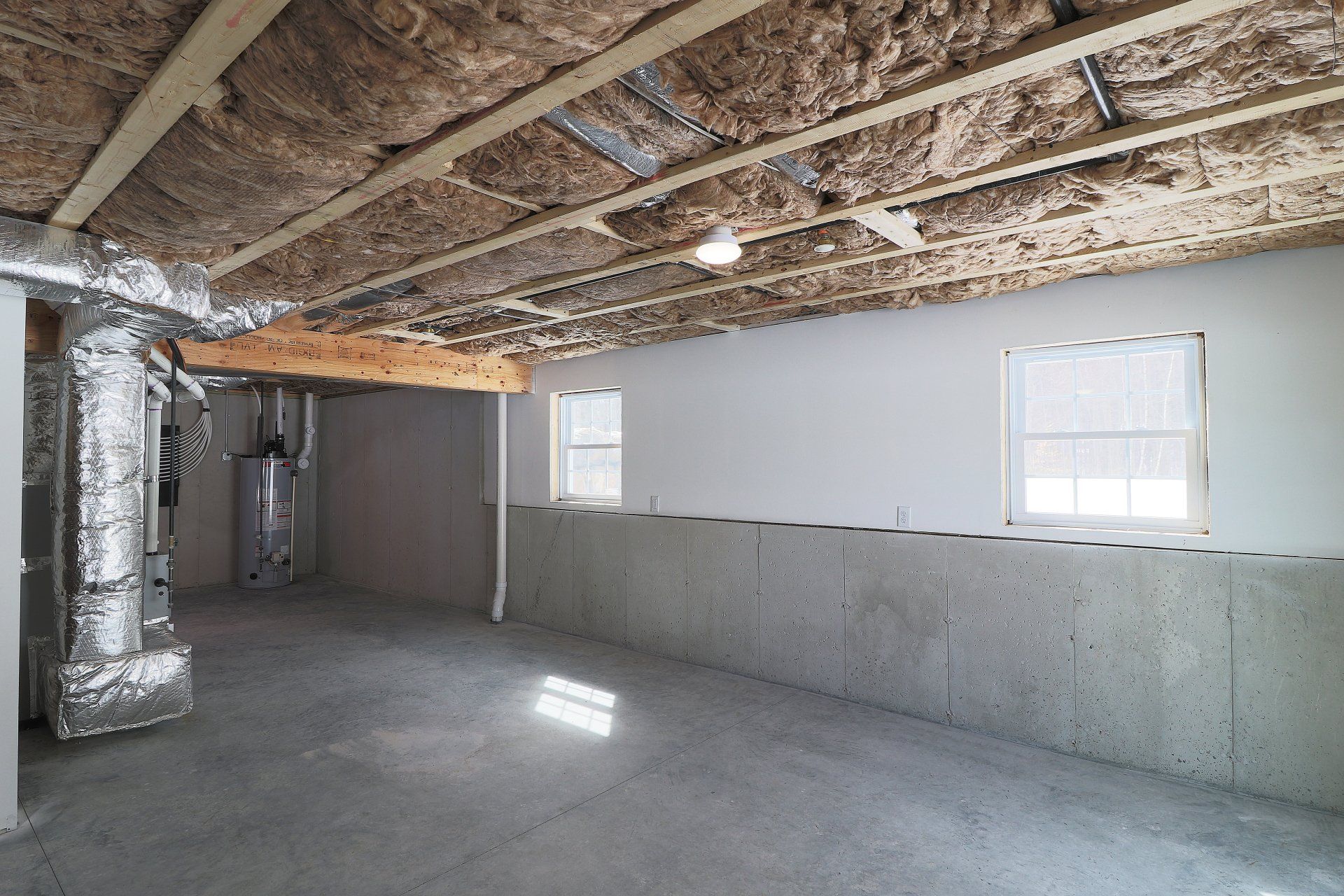 An empty basement with a lot of insulation and windows.