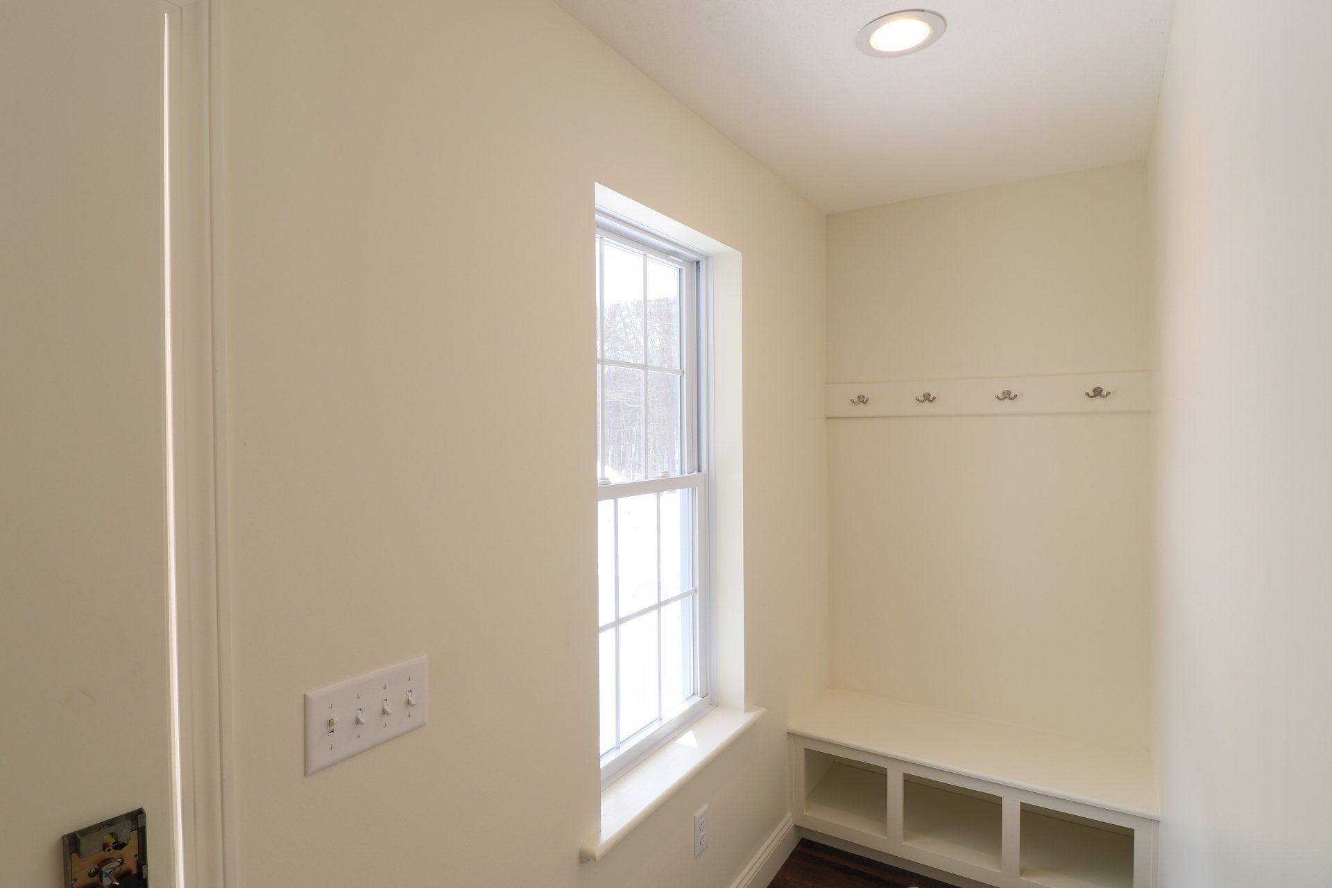 A white room with a window and a bench.