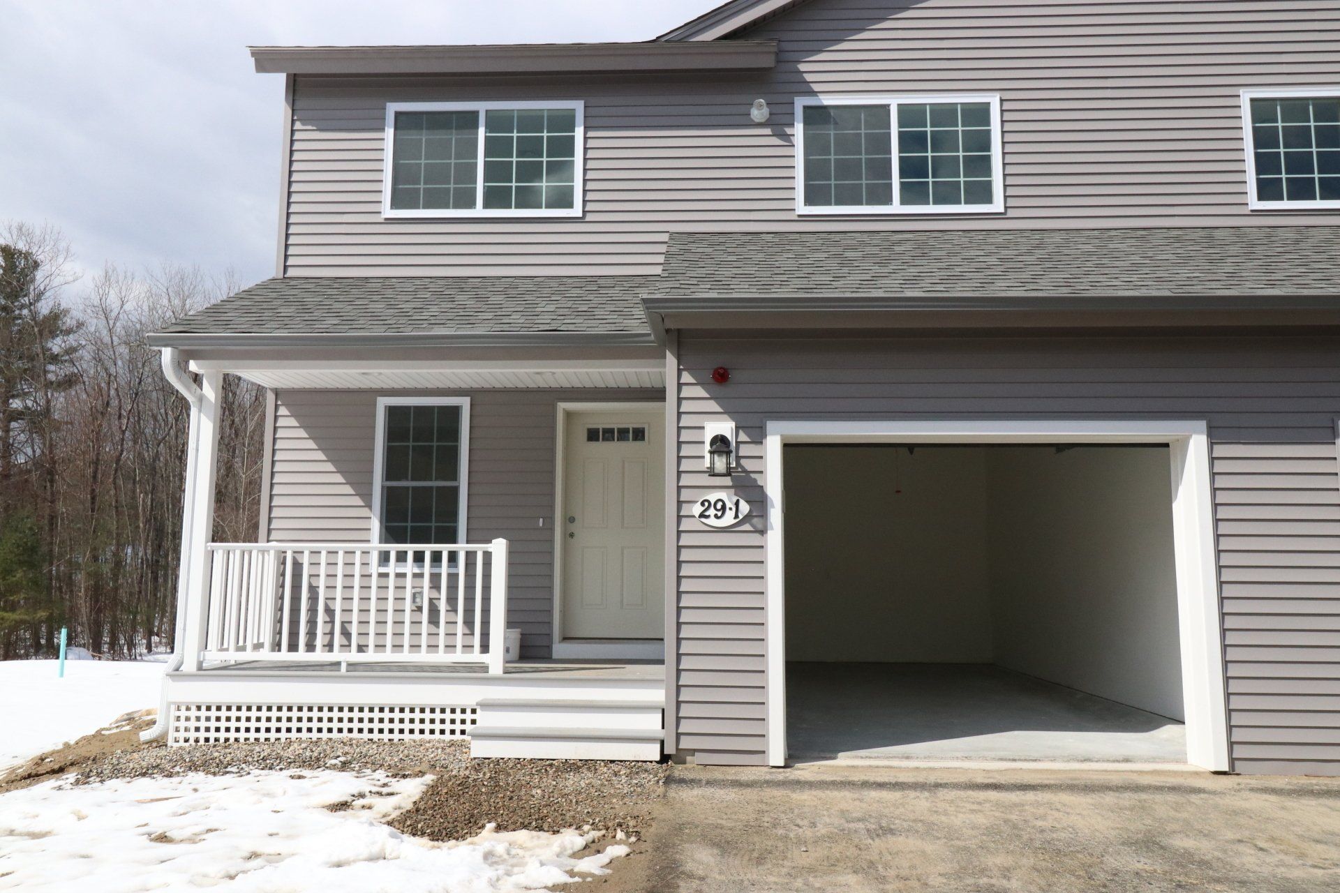 A gray house with a white porch and a garage