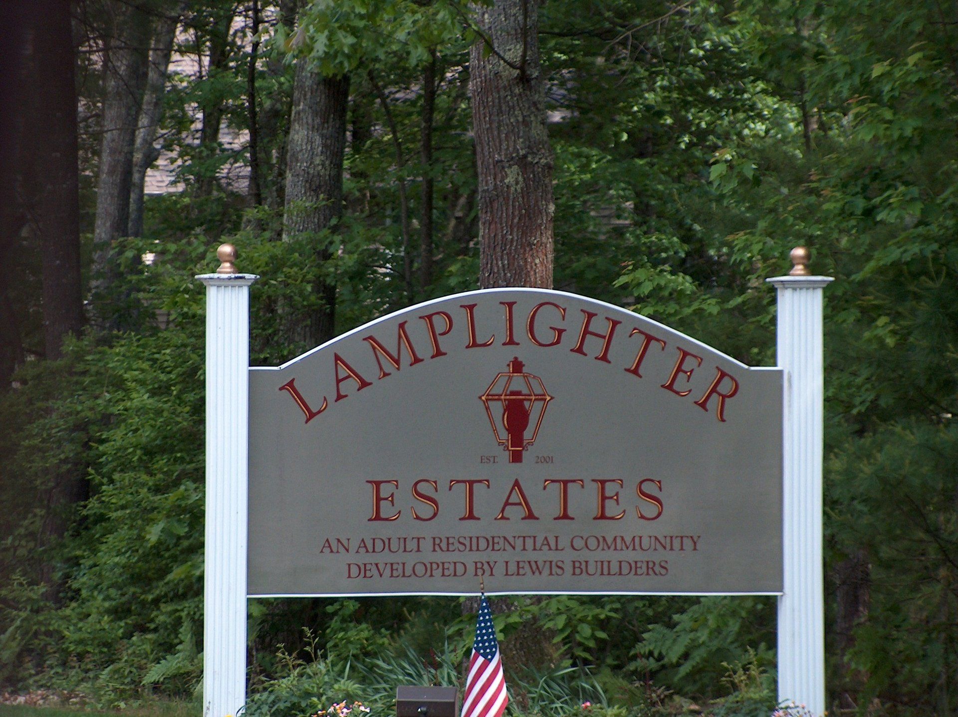 A sign for lamplighter estates is surrounded by trees
