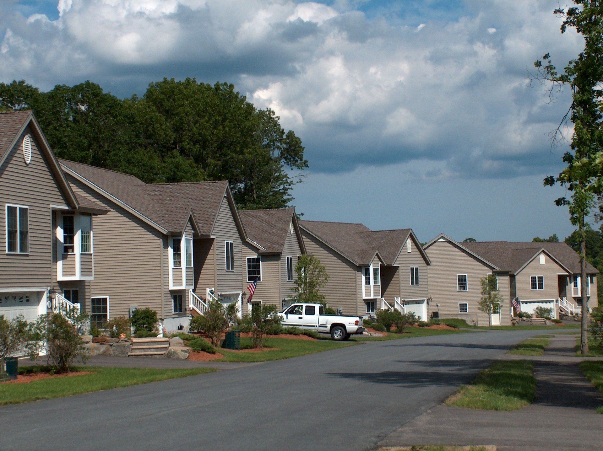 A white truck is parked in front of a row of houses