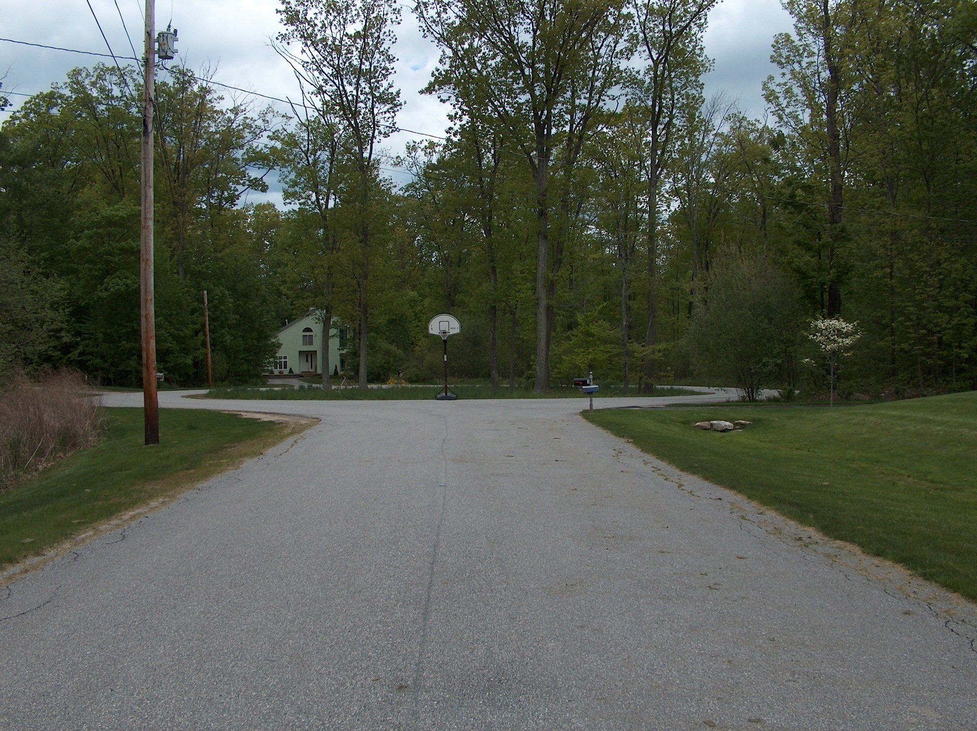 A road with a basketball hoop in the middle of it