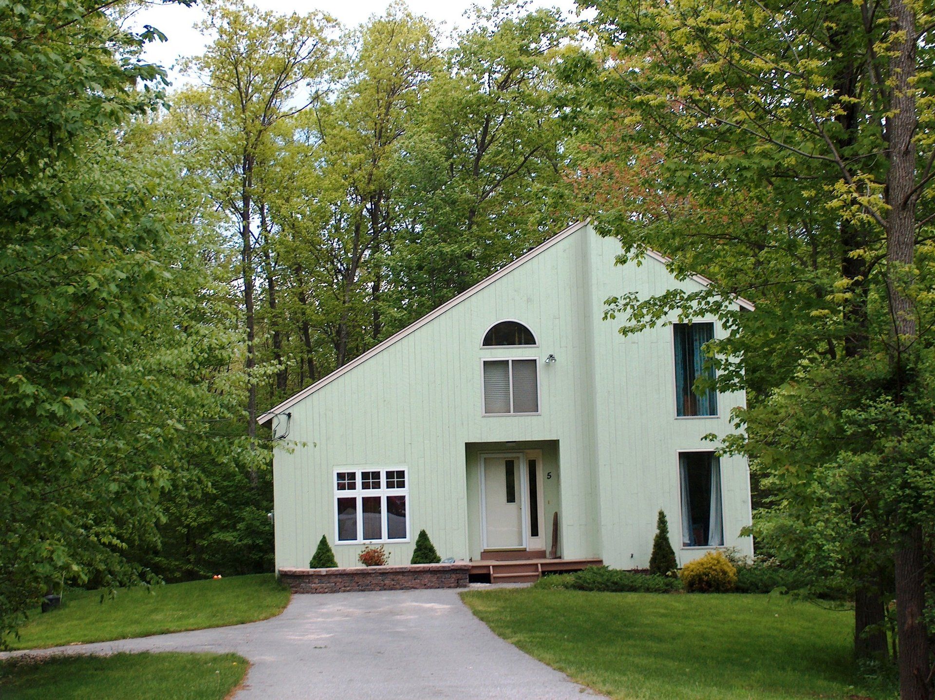 A green house is surrounded by trees and grass