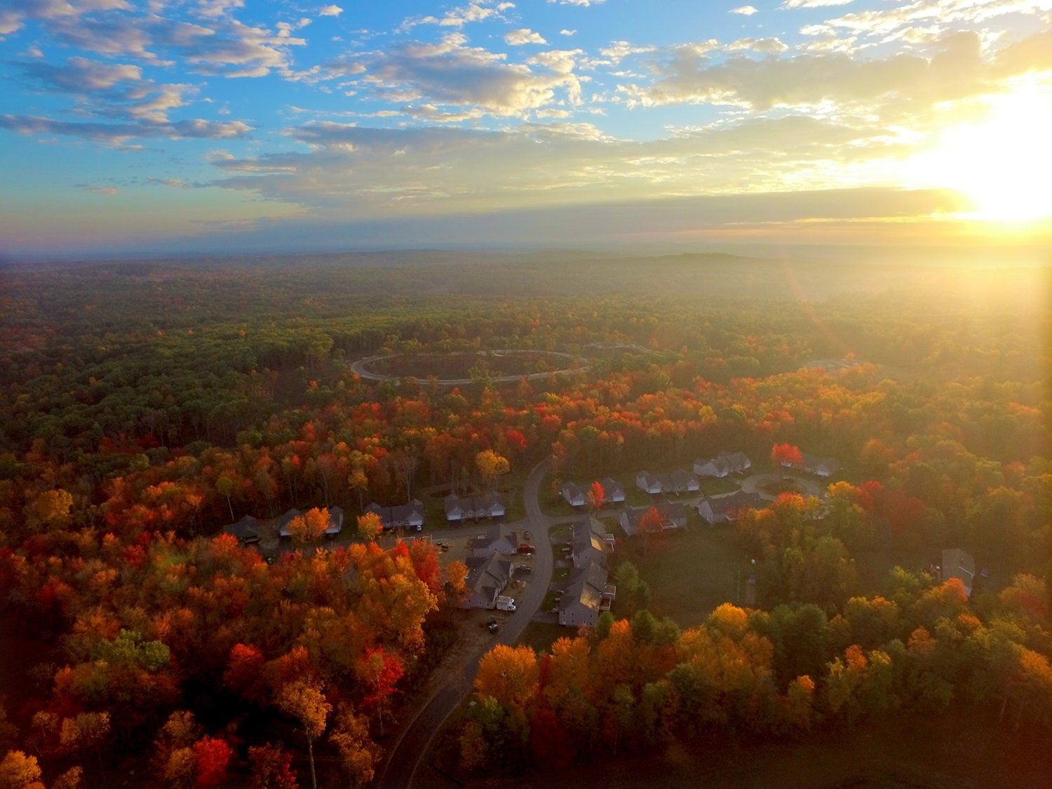 An aerial view of a residential area surrounded by trees at sunset.
