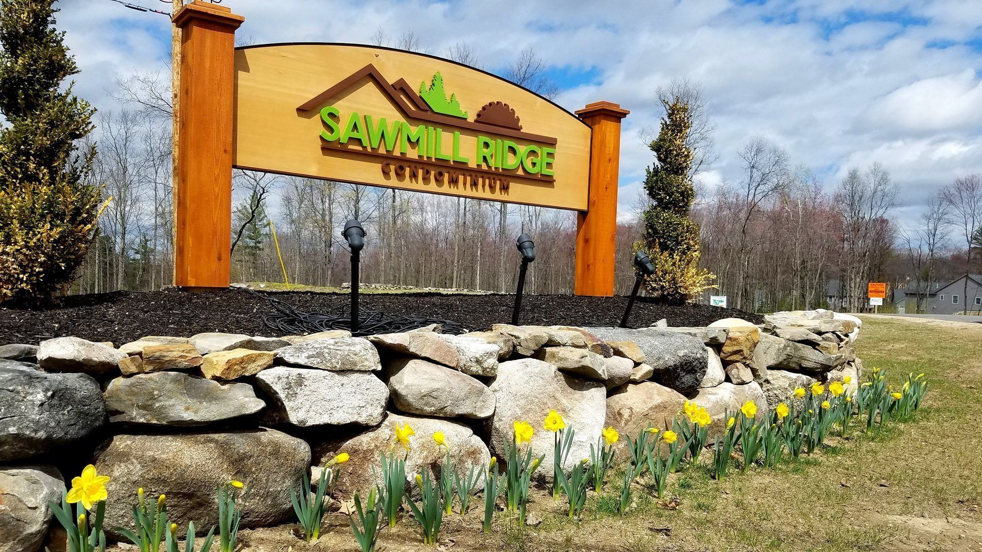 A wooden sign is sitting on top of a rock wall.