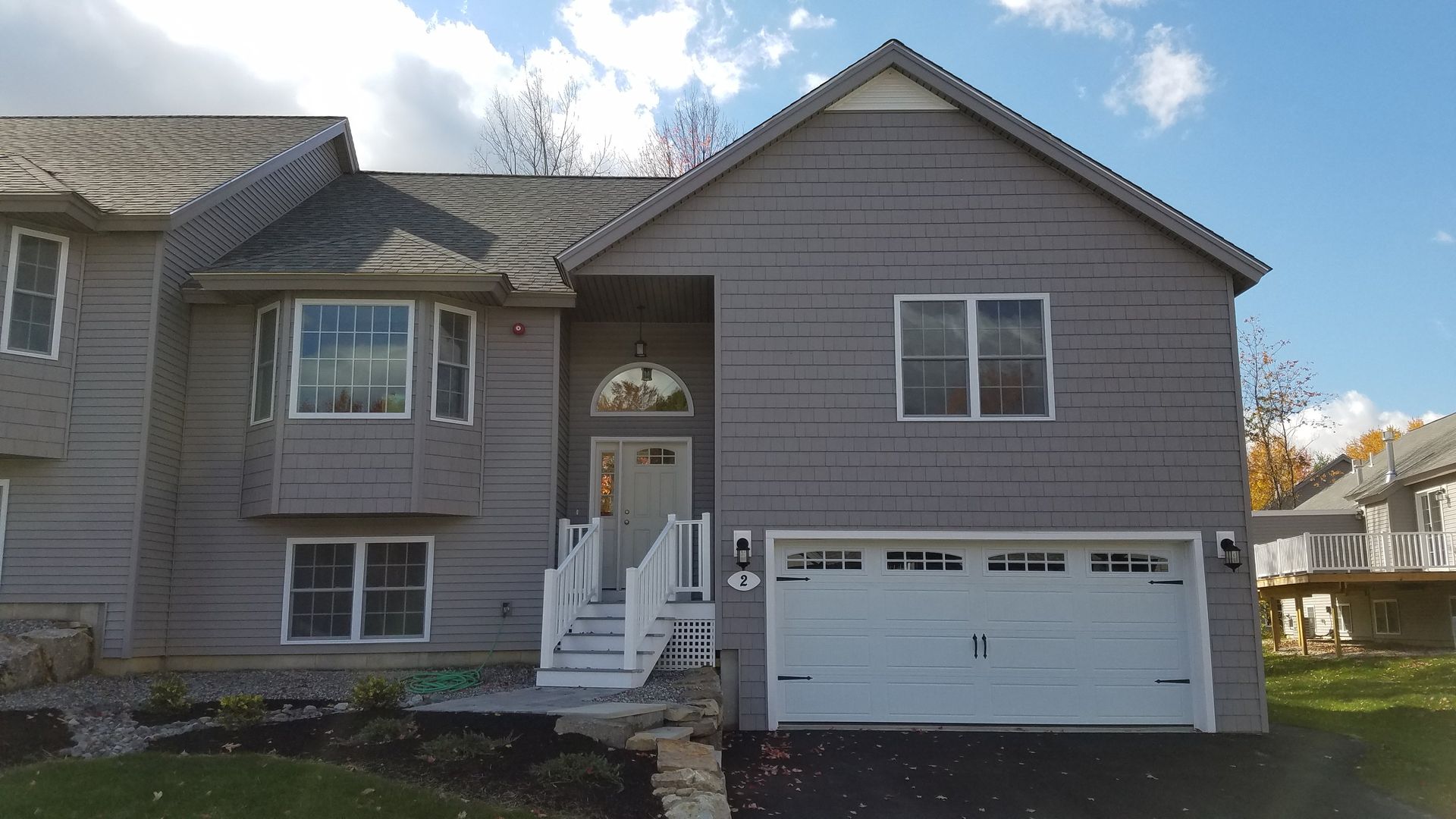 A gray house with a white garage door and stairs