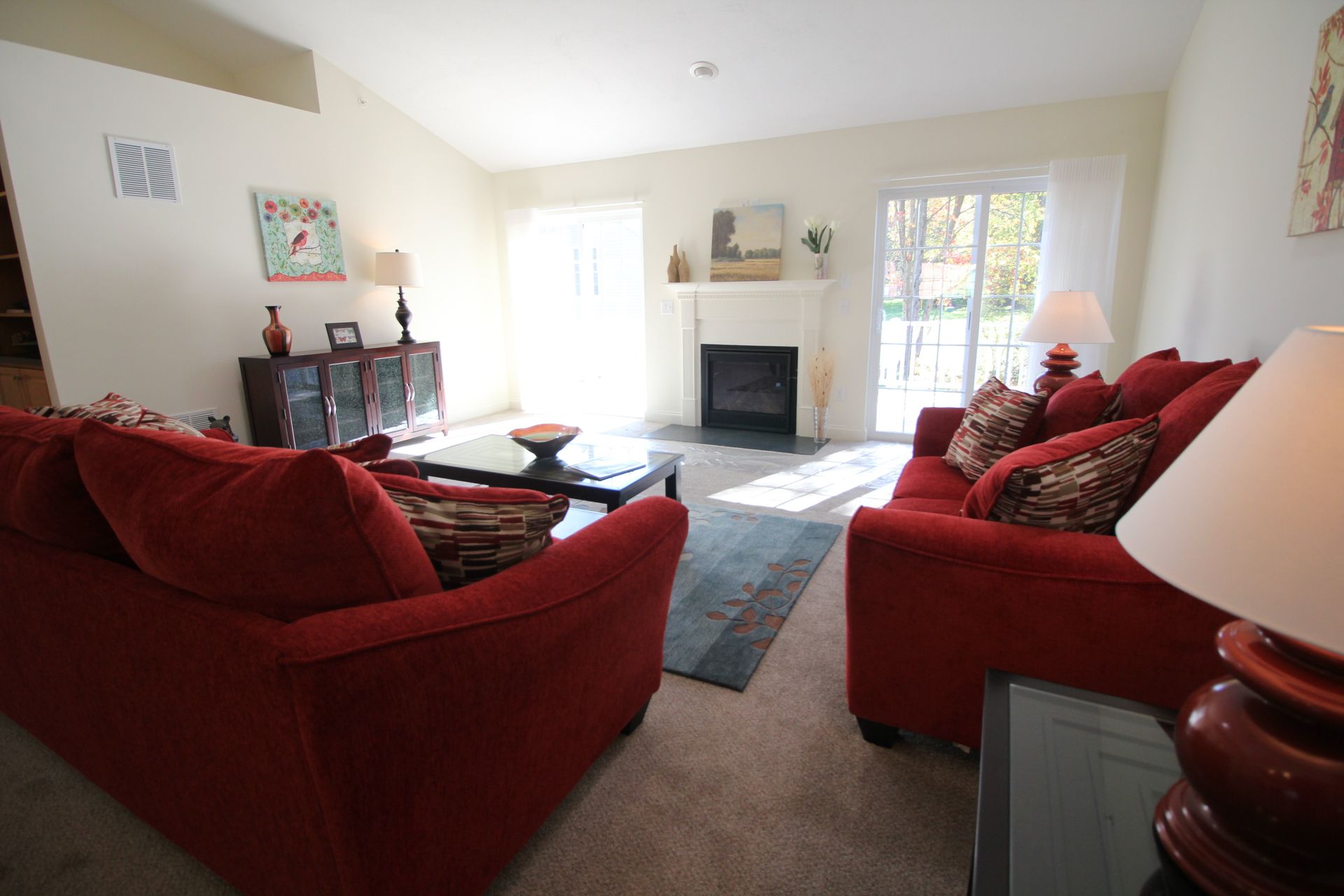 A living room with two red couches and a fireplace