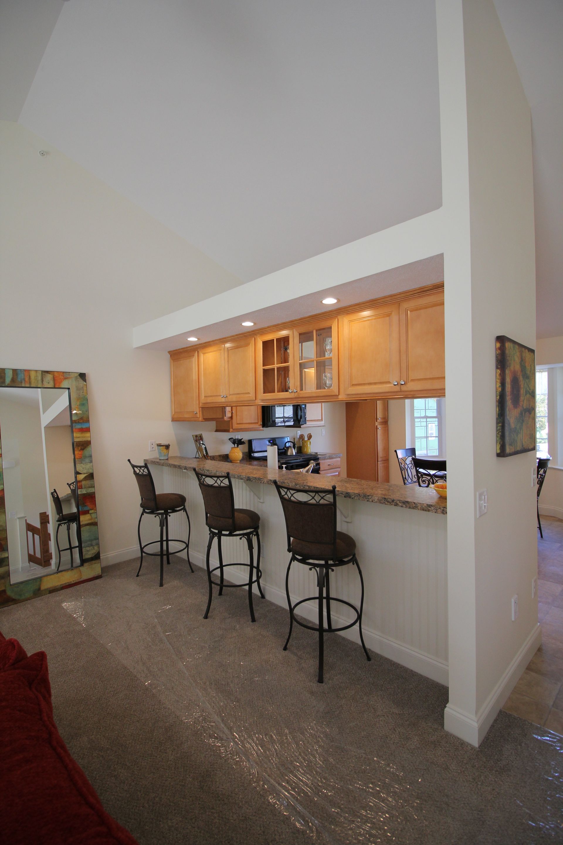 A kitchen with a bar , chairs and a mirror.