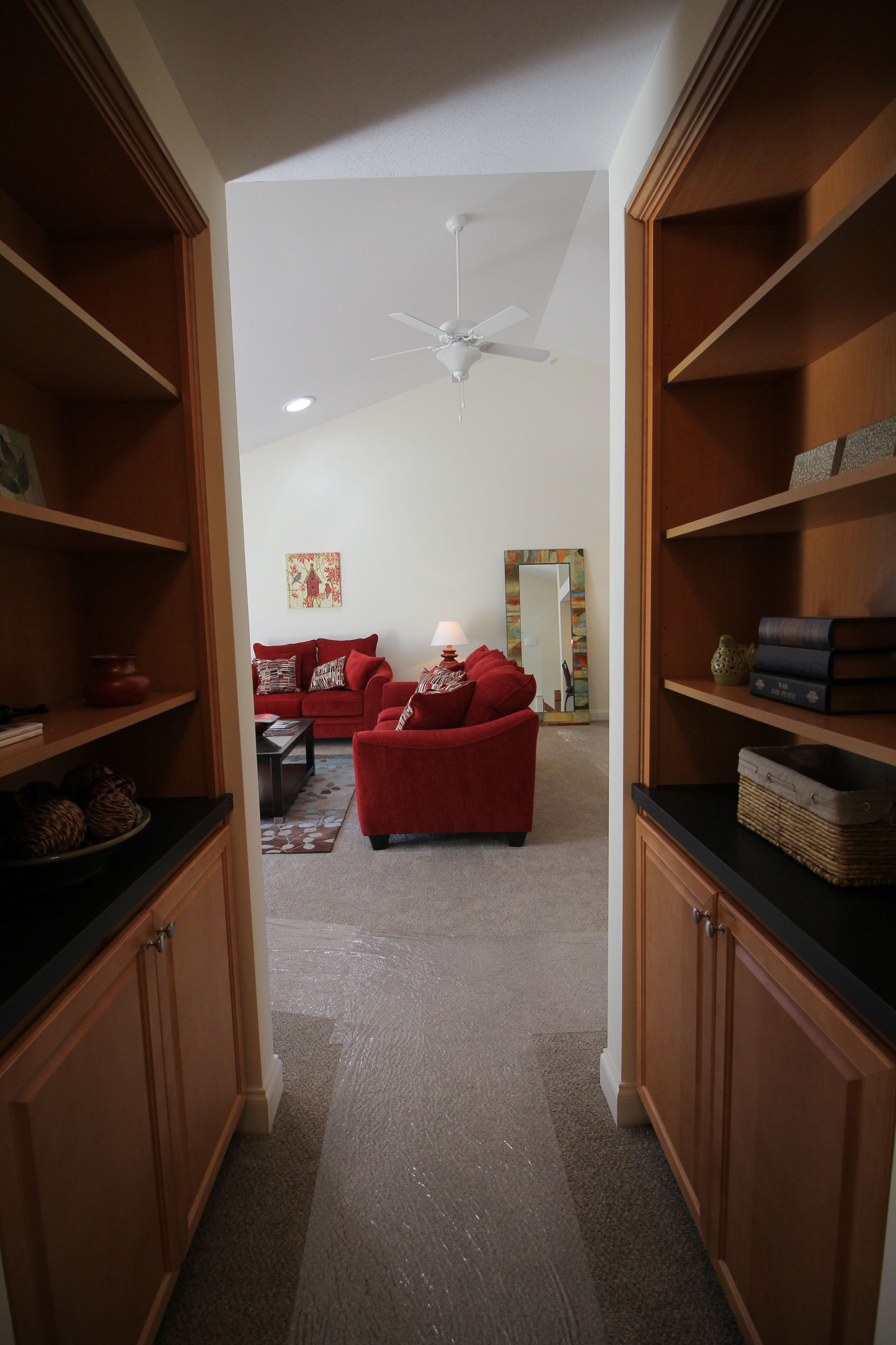 A hallway leading to a living room with a red couch