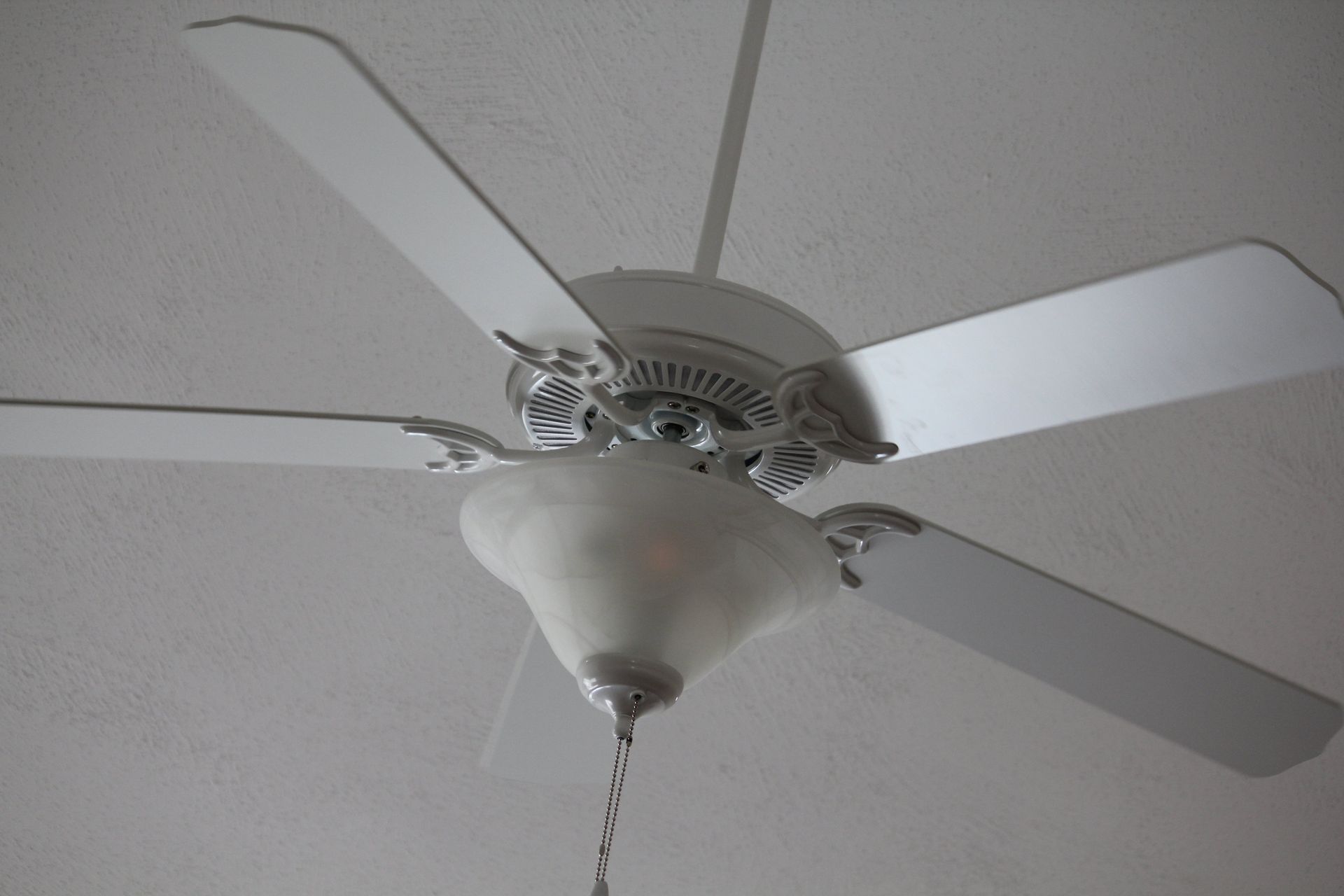 A white ceiling fan with a light attached to it