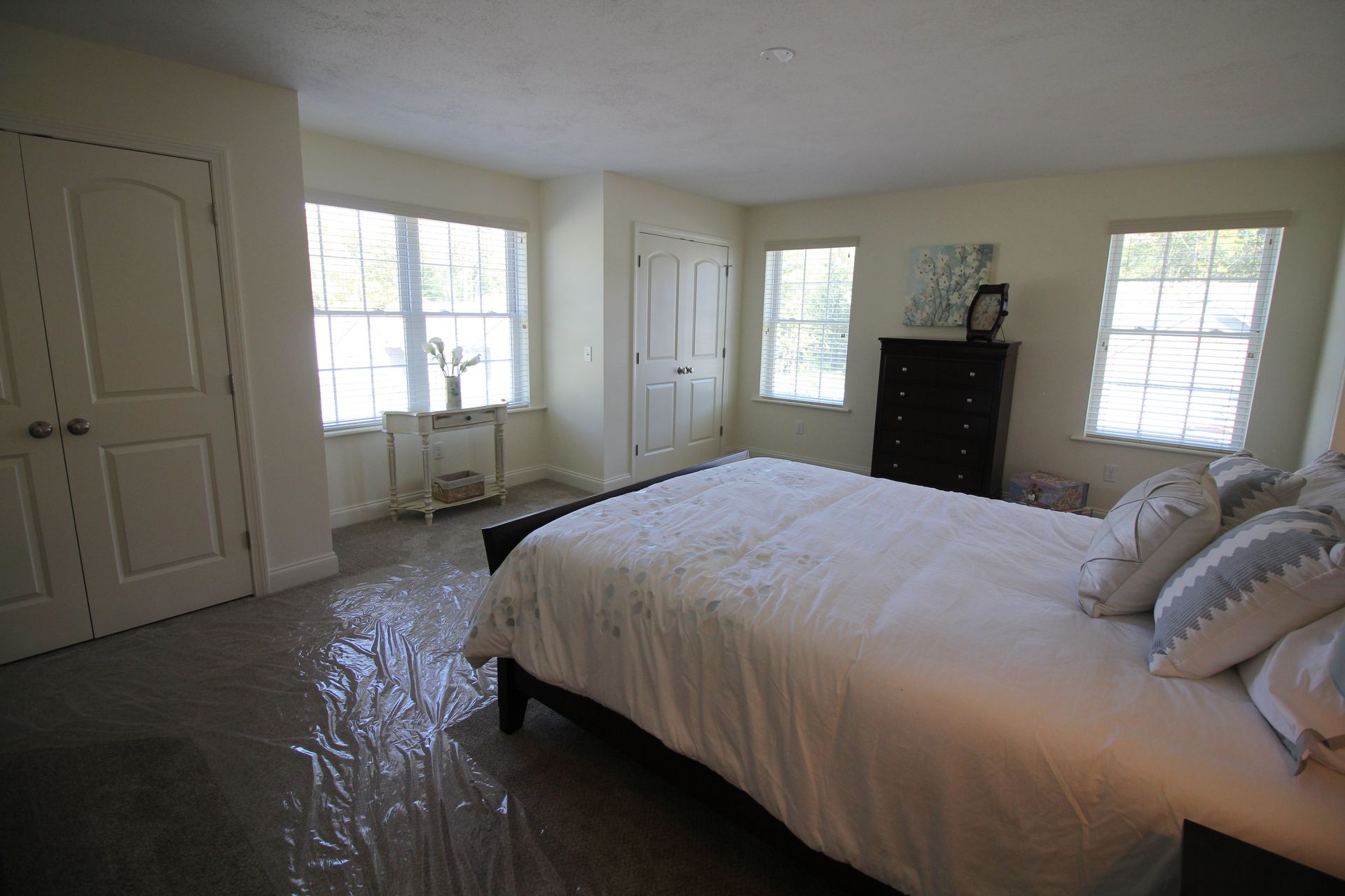 A bedroom with a bed , dresser , and two windows.