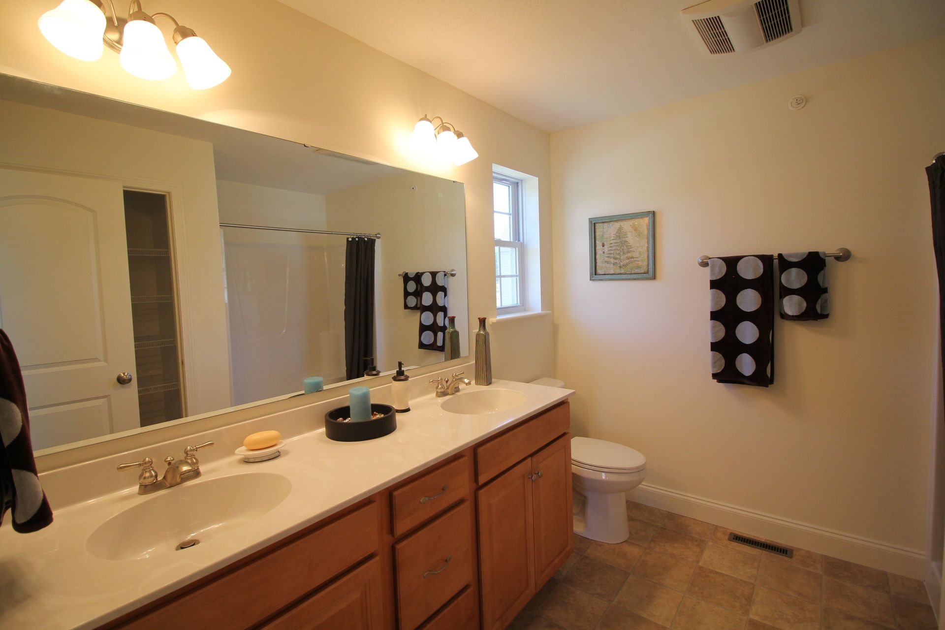 A bathroom with two sinks , a toilet and a large mirror