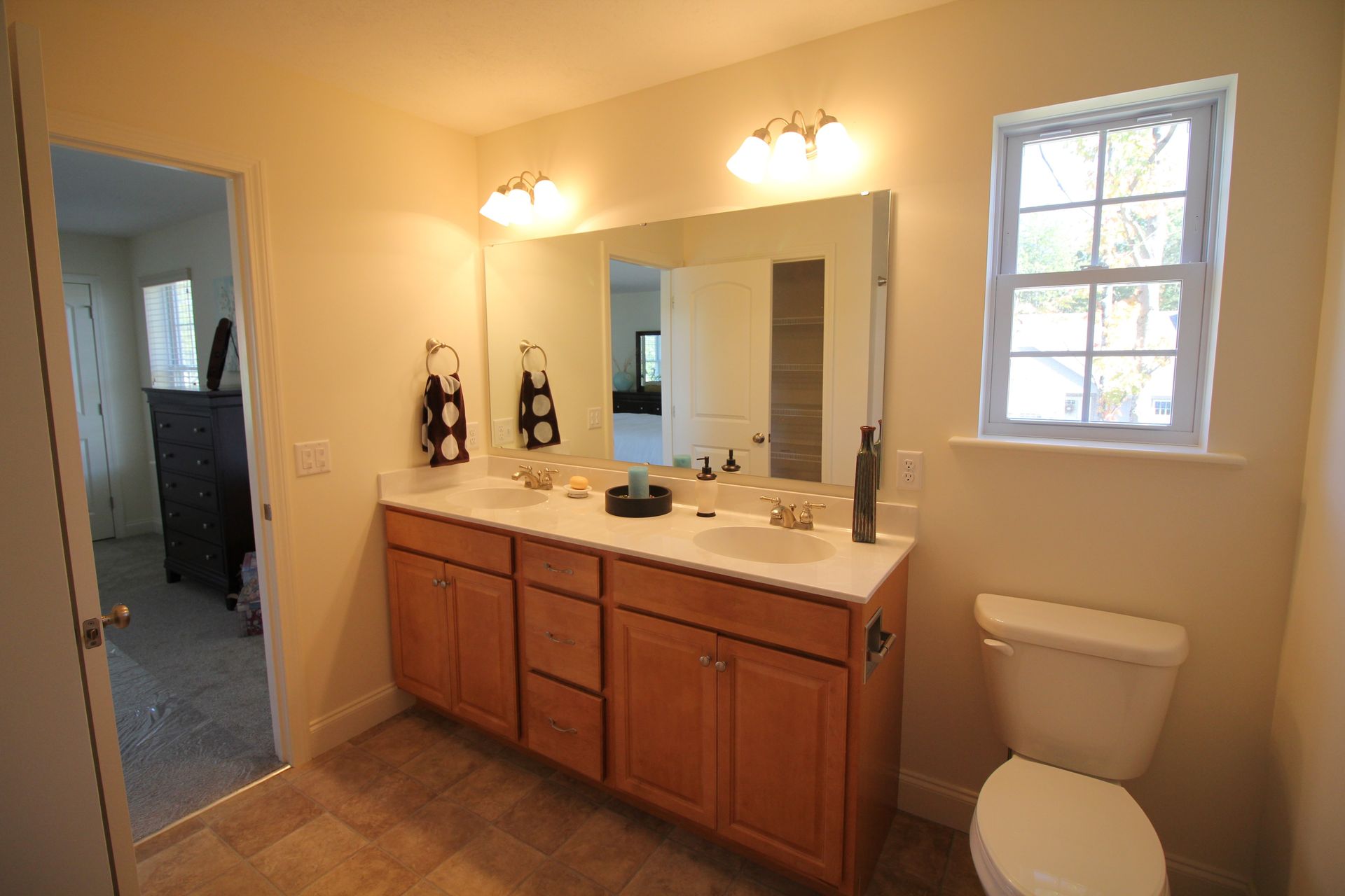 A bathroom with two sinks , a toilet and a window.