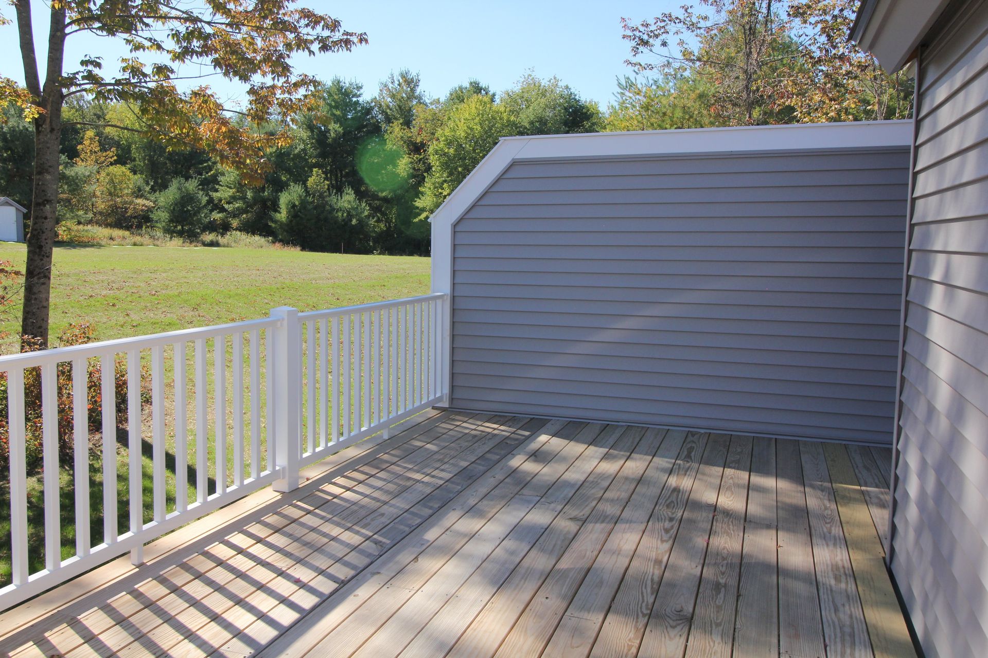 An empty deck with a white railing and a house in the background