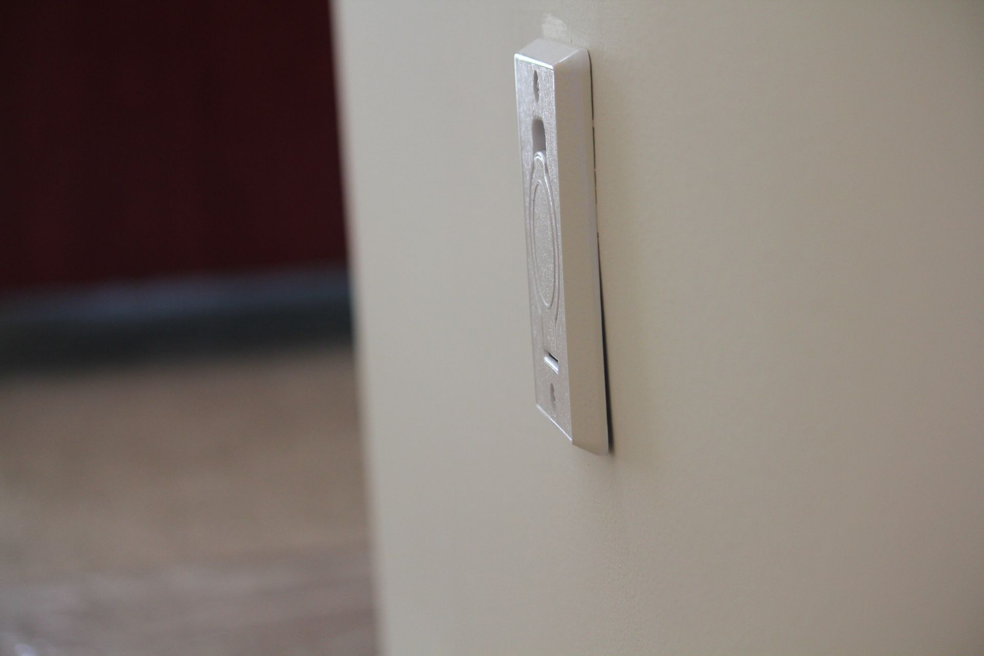 A remote control is hanging on a white wall.
