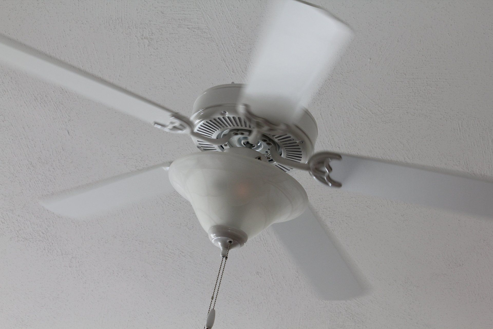 A white ceiling fan is spinning on a white ceiling.