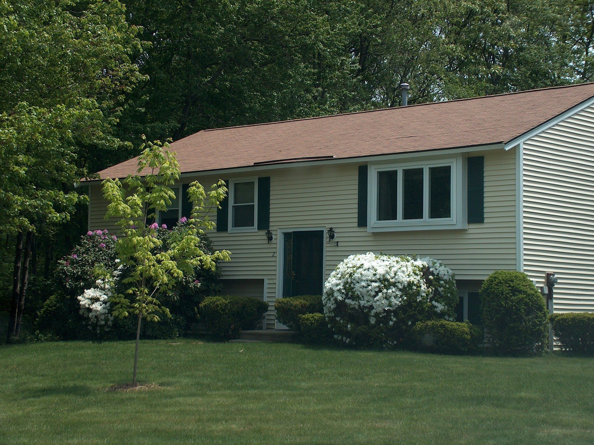 A white house with a brown roof and black shutters