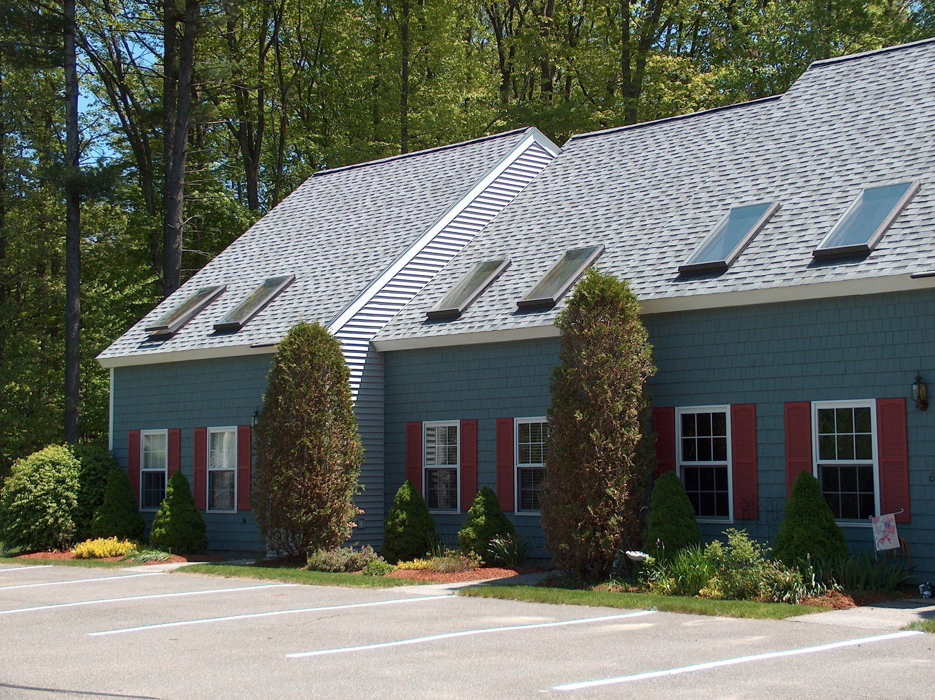 A blue house with red shutters and a gray roof