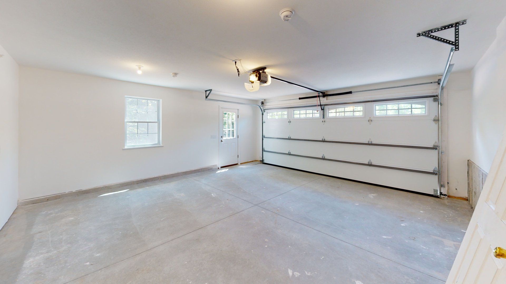 An empty garage with a garage door open and a window.