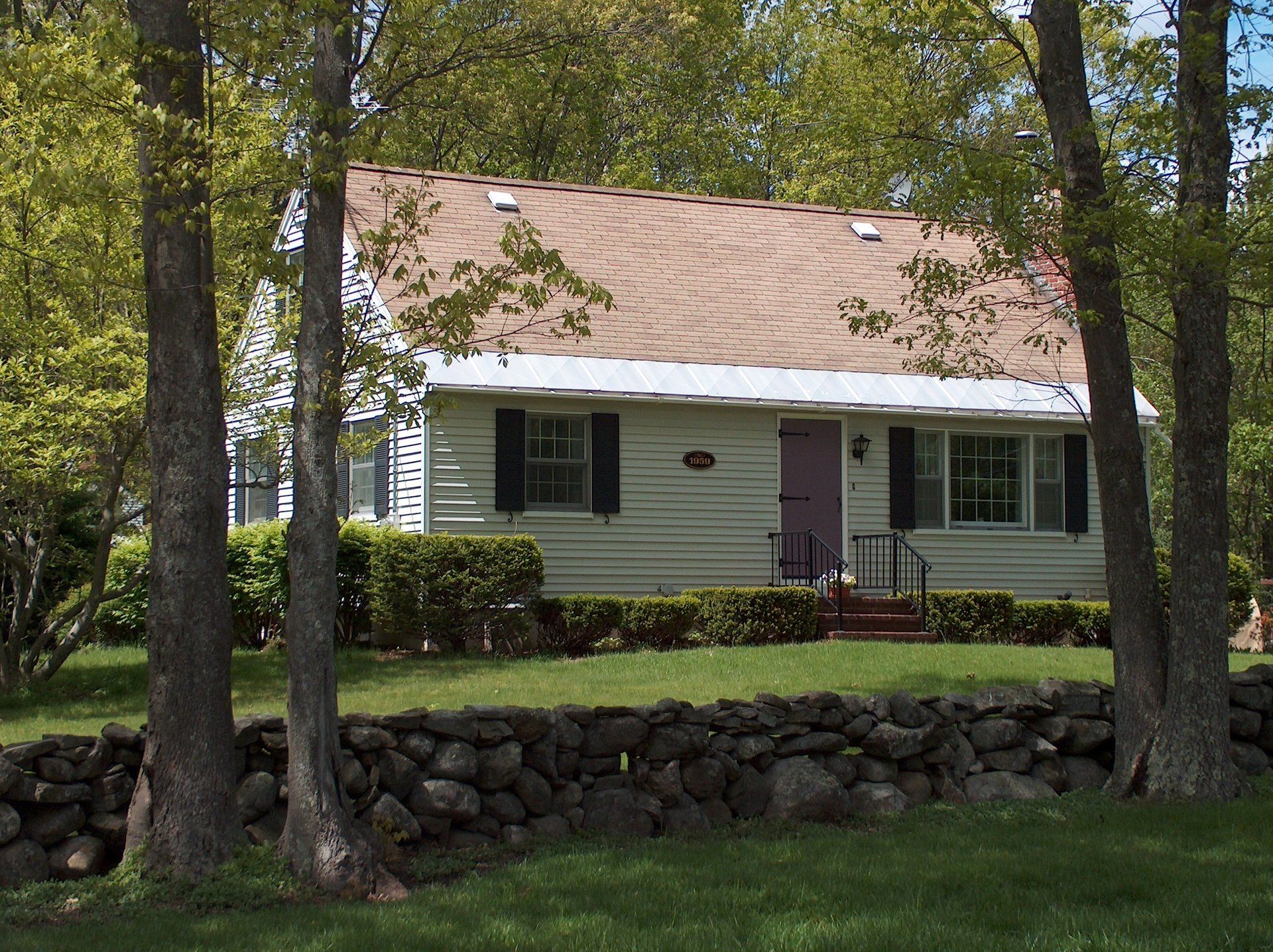 A white house with a brown roof is surrounded by trees