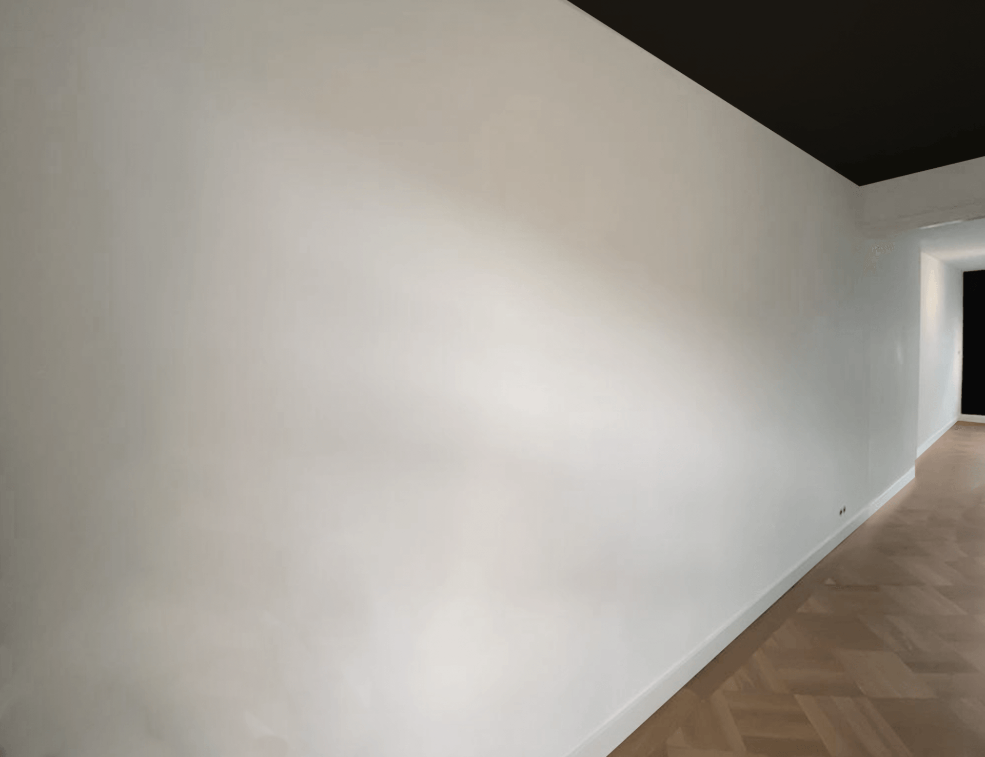 Een lege gang met witte muren en een zwart plafond.