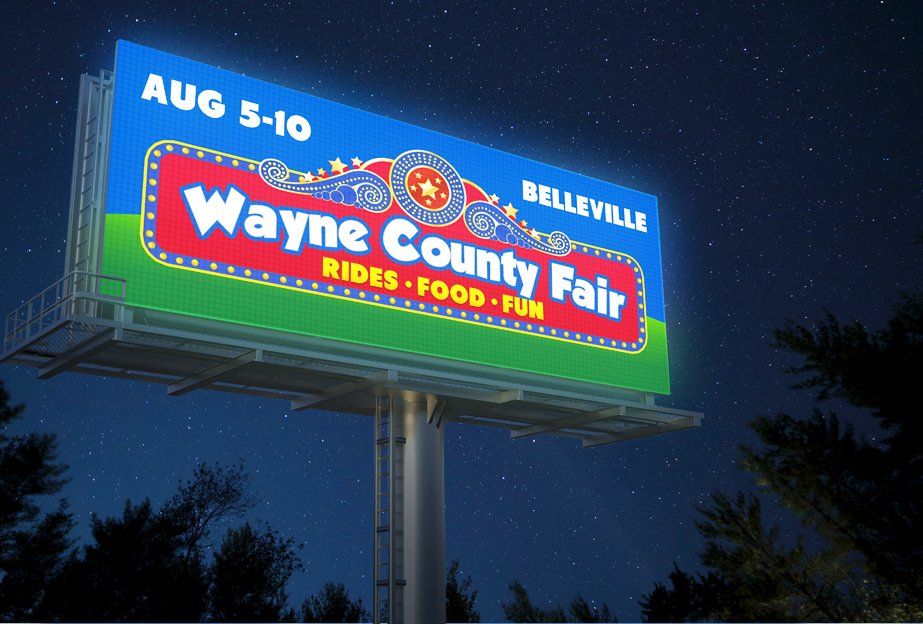 A billboard for the wayne county fair is lit up at night
