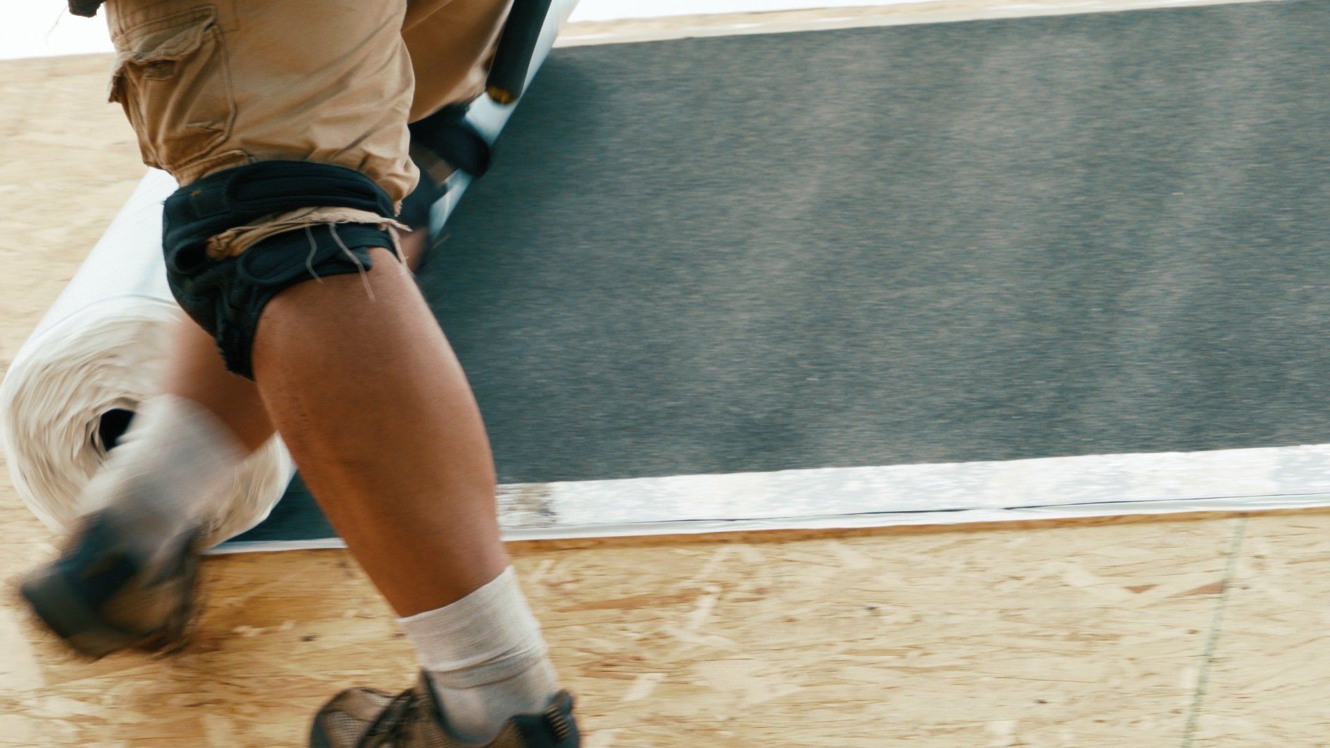 A person is carrying a roll of carpet on their feet.
