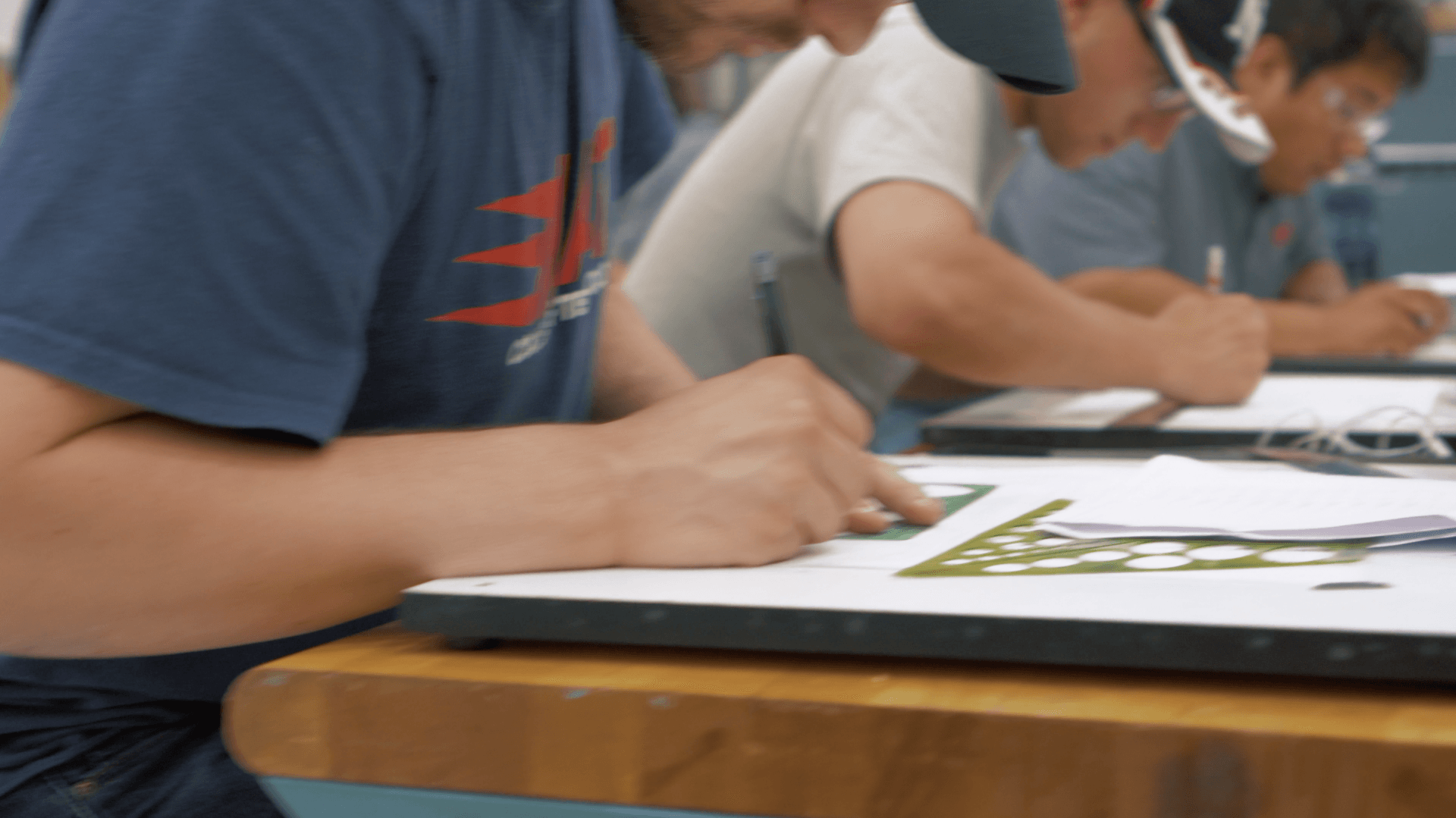 A group of people are sitting at a table writing on a piece of paper.