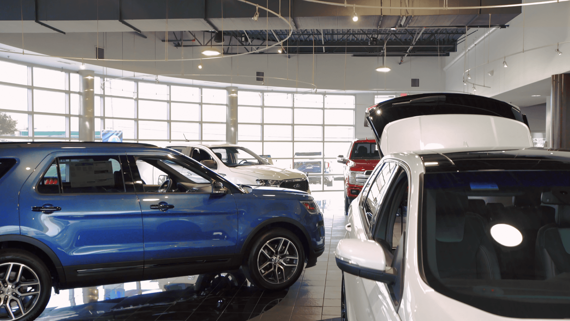 A row of cars are parked in a showroom.